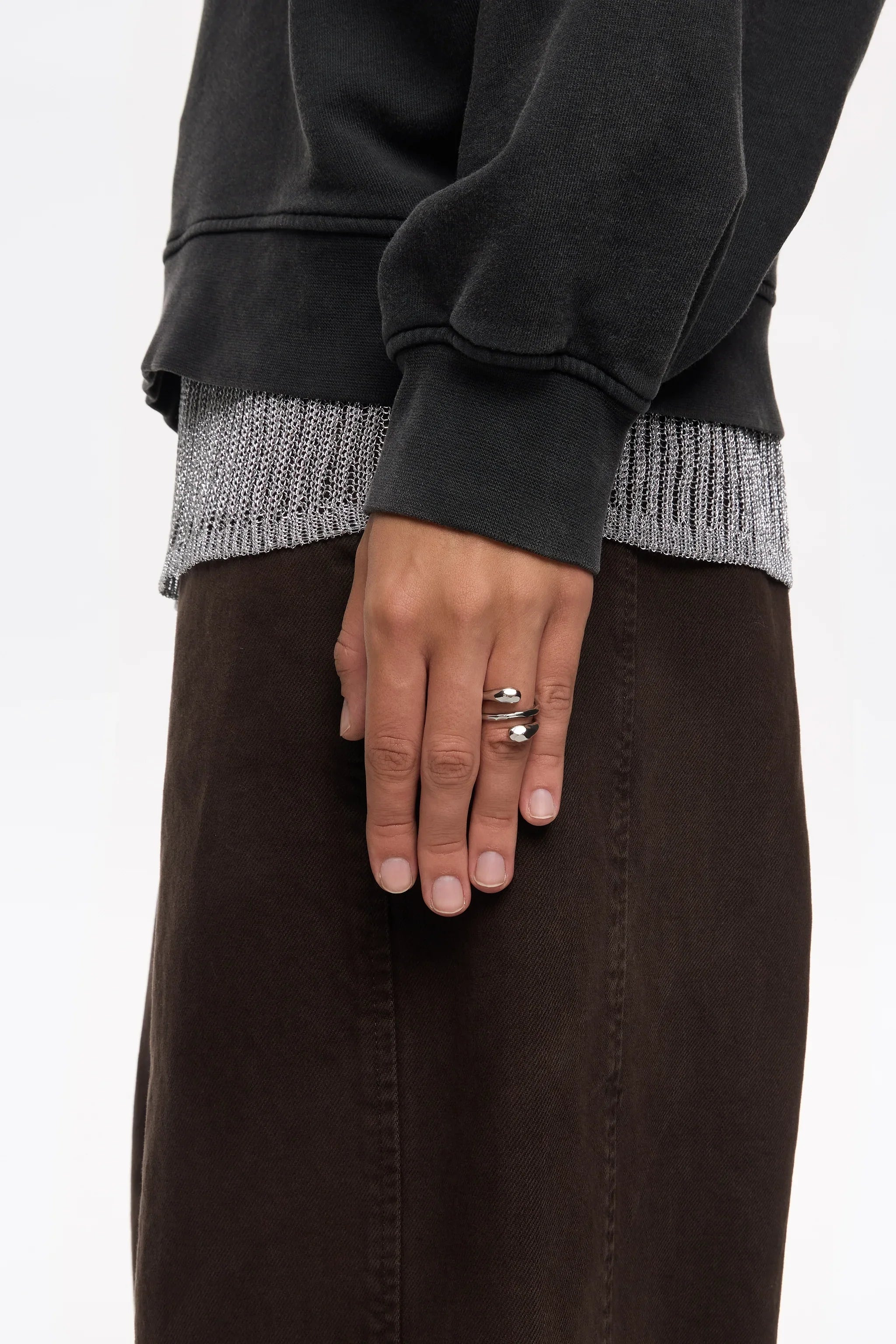 יד עם טבעת כסף, חולצה שחורה ומכנסיים כהים מאת CHOZEN, אופנה יוקרתית בישראל