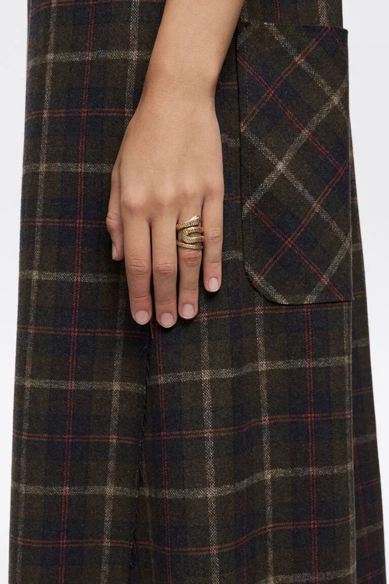 יד עם טבעת זהב על שמלה משובצת בגוונים כהים, אופנה יוקרתית CHOZEN