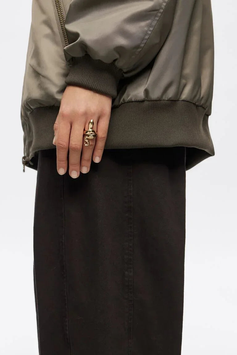 יד עם ז'קט ירוק טבעי וטבעת זהב בעיצוב נחש, אופנה CHOZEN, תכשיטים טרנדיים בישראל