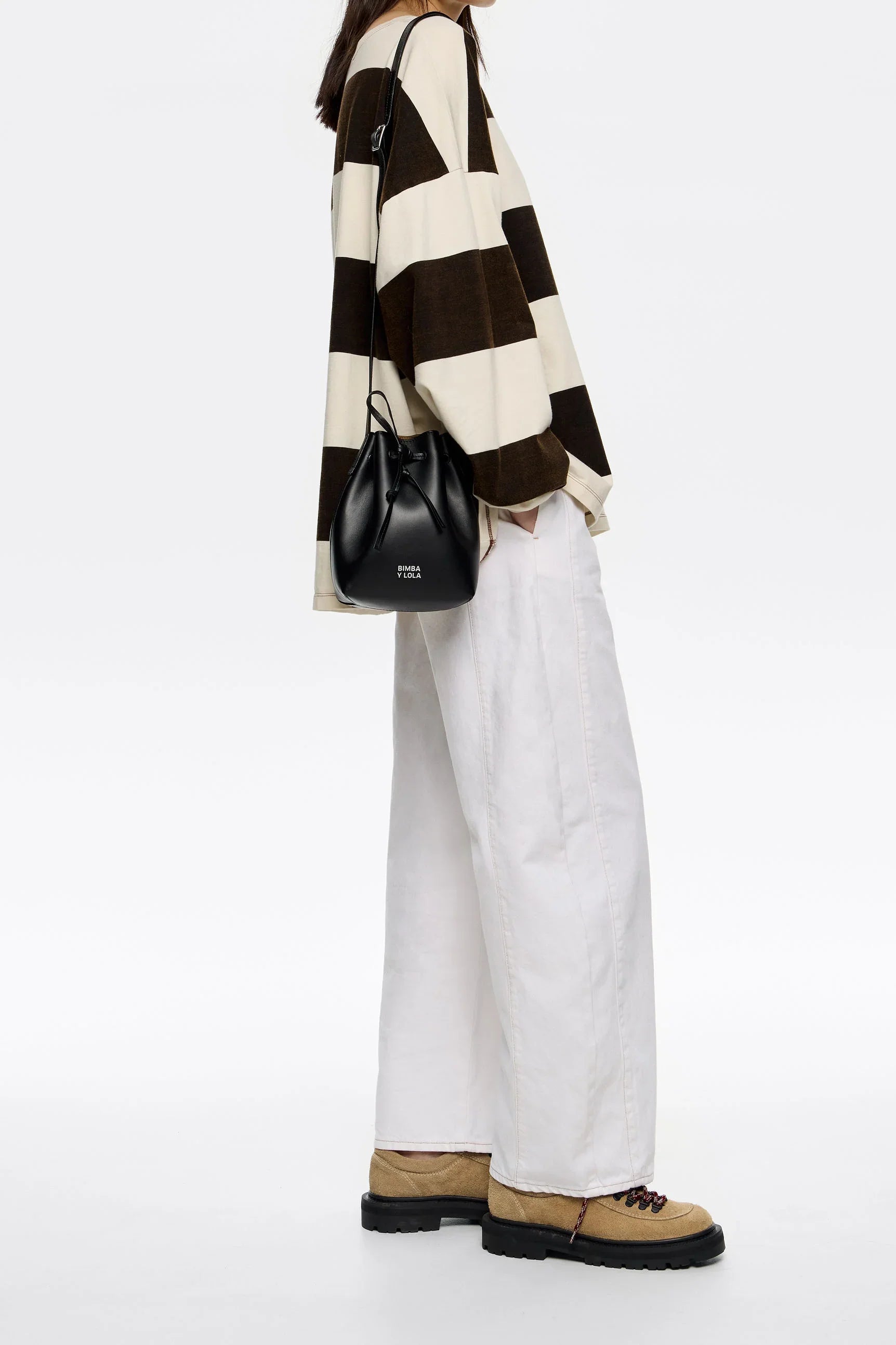 אופנת נשים: חולצת פסים שחור-לבן, מכנסיים לבנים, תיק שחור ושם המותג CHOZEN