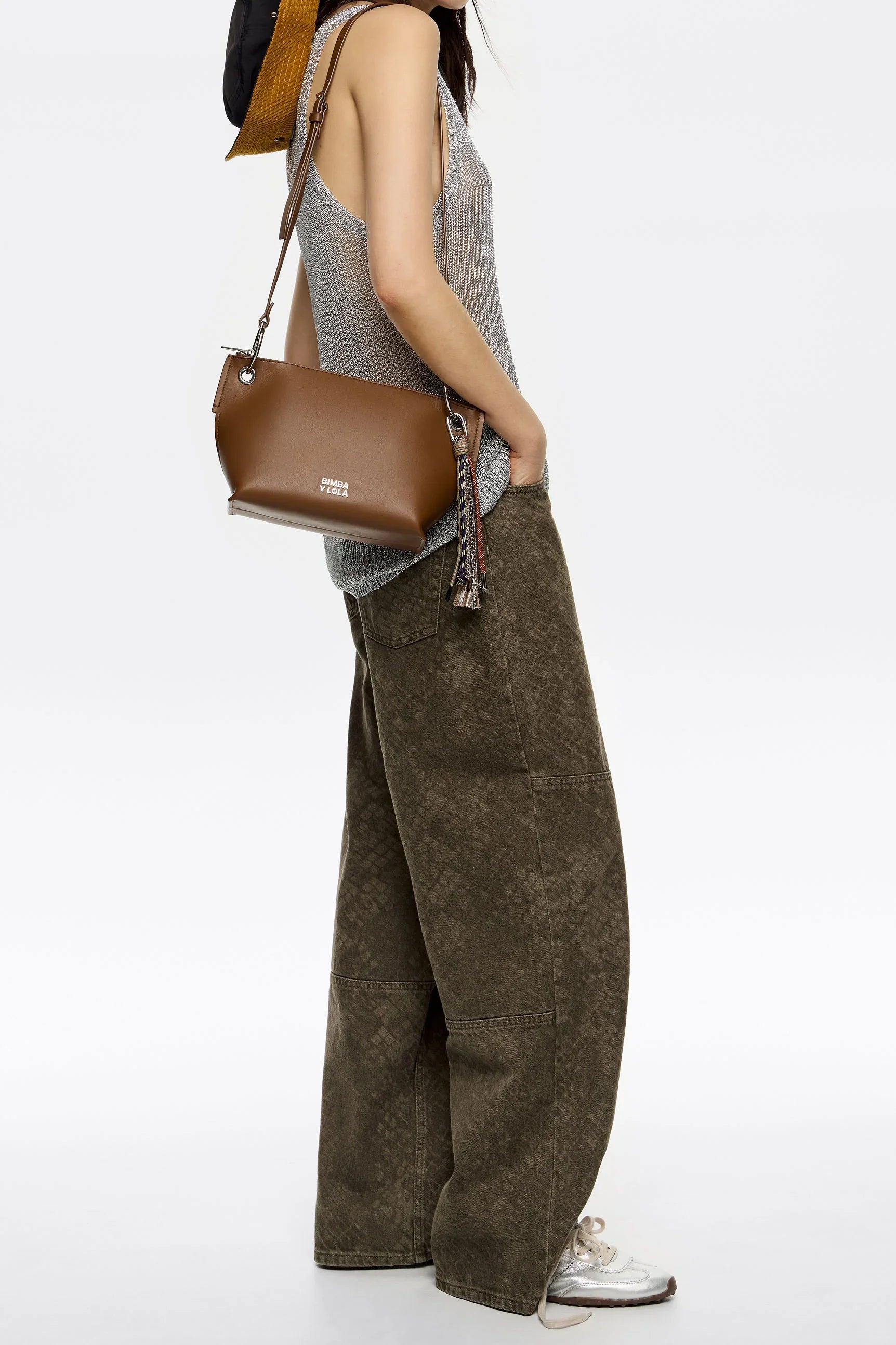 תיק חום לנשים Bimba Y Lola על דוגמנית עם גופיה אפורה ומכנסיים רחבים, אופנת CHOZEN