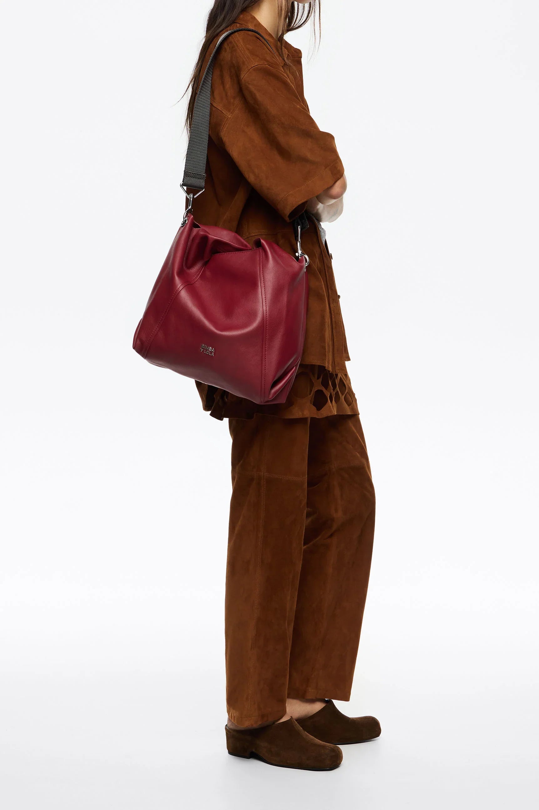 אישה לובשת חליפת קטיפה חומה ונושאת תיק עור אדום אופנתי בעיצוב יוקרתי, CHOZEN