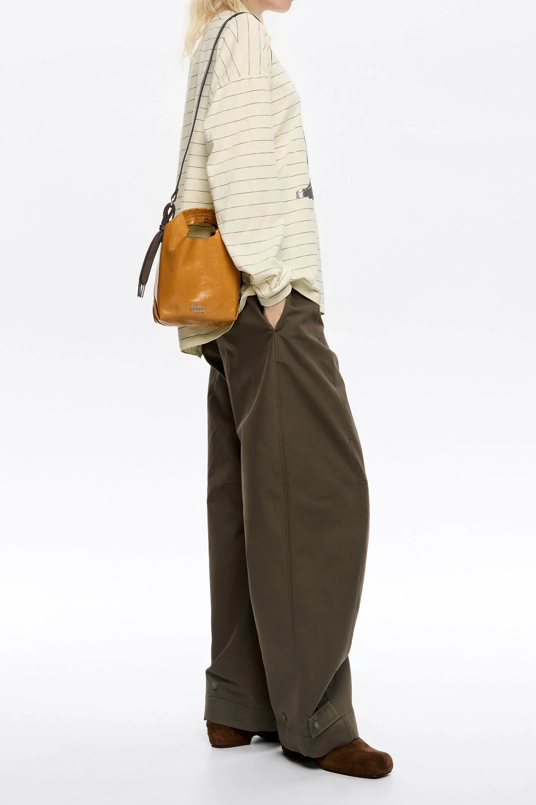 אישה בלבוש אופנתי עם תיק עור כתום, סווטשרט פסים ומכנסיים רחבים, צילום קמפיין CHOZEN