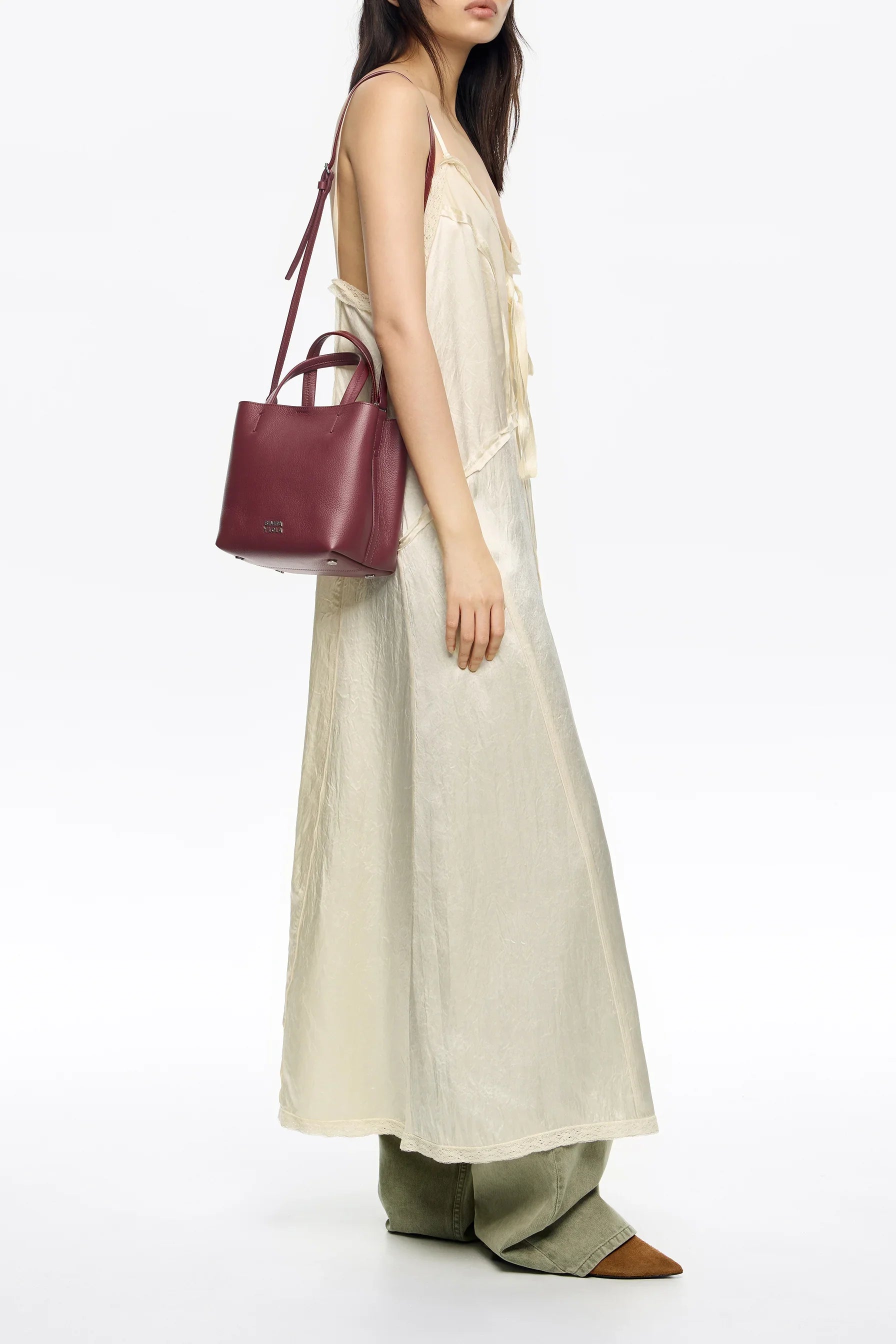 אישה עם שמלה בהירה ותיק עור בורדו על כתף, צילום אופנה CHOZEN