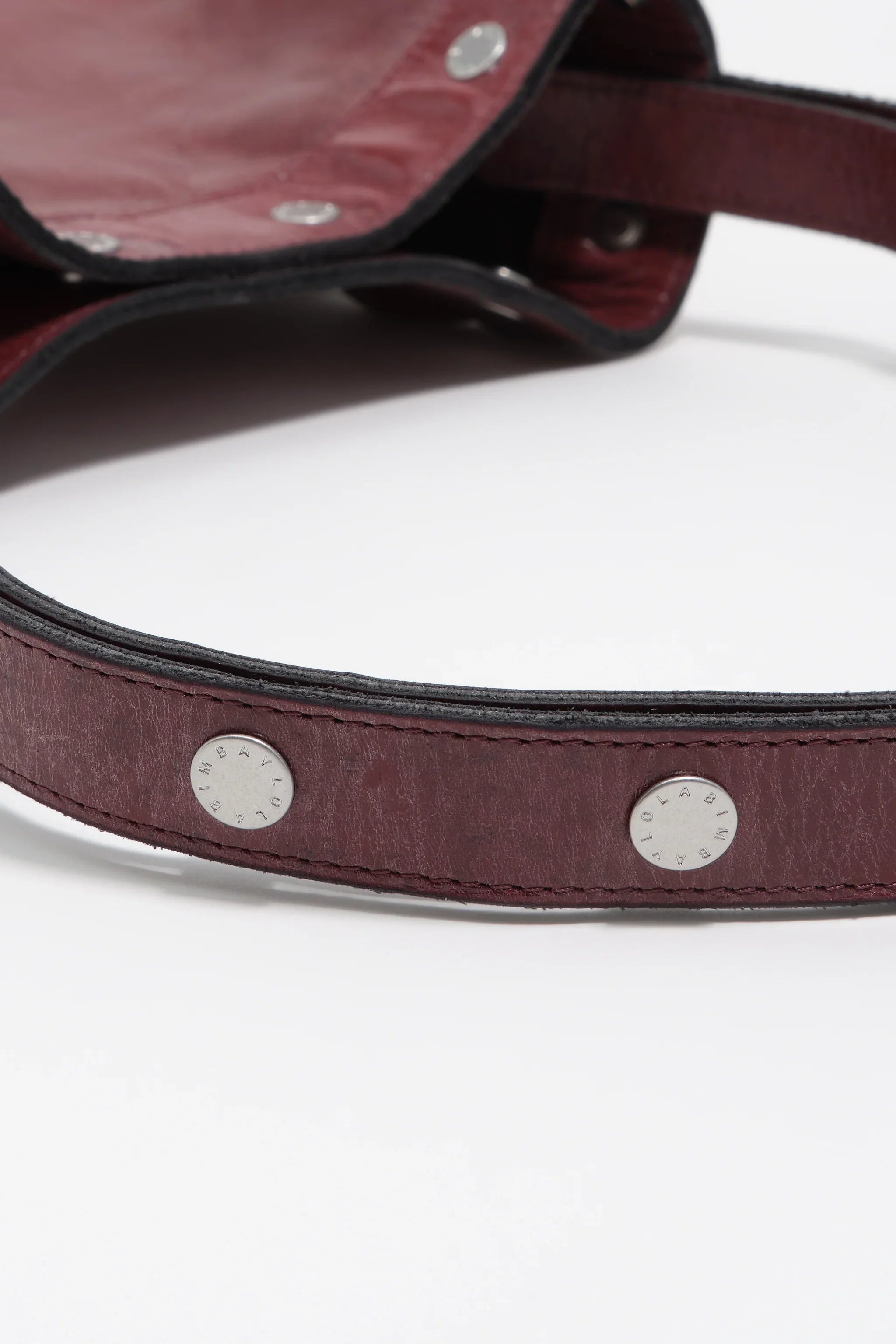 תקריב של תיק עור בורדו עם ניטים כסופים, אופנה יוקרתית ב-CHOZEN קבוצה אלפא