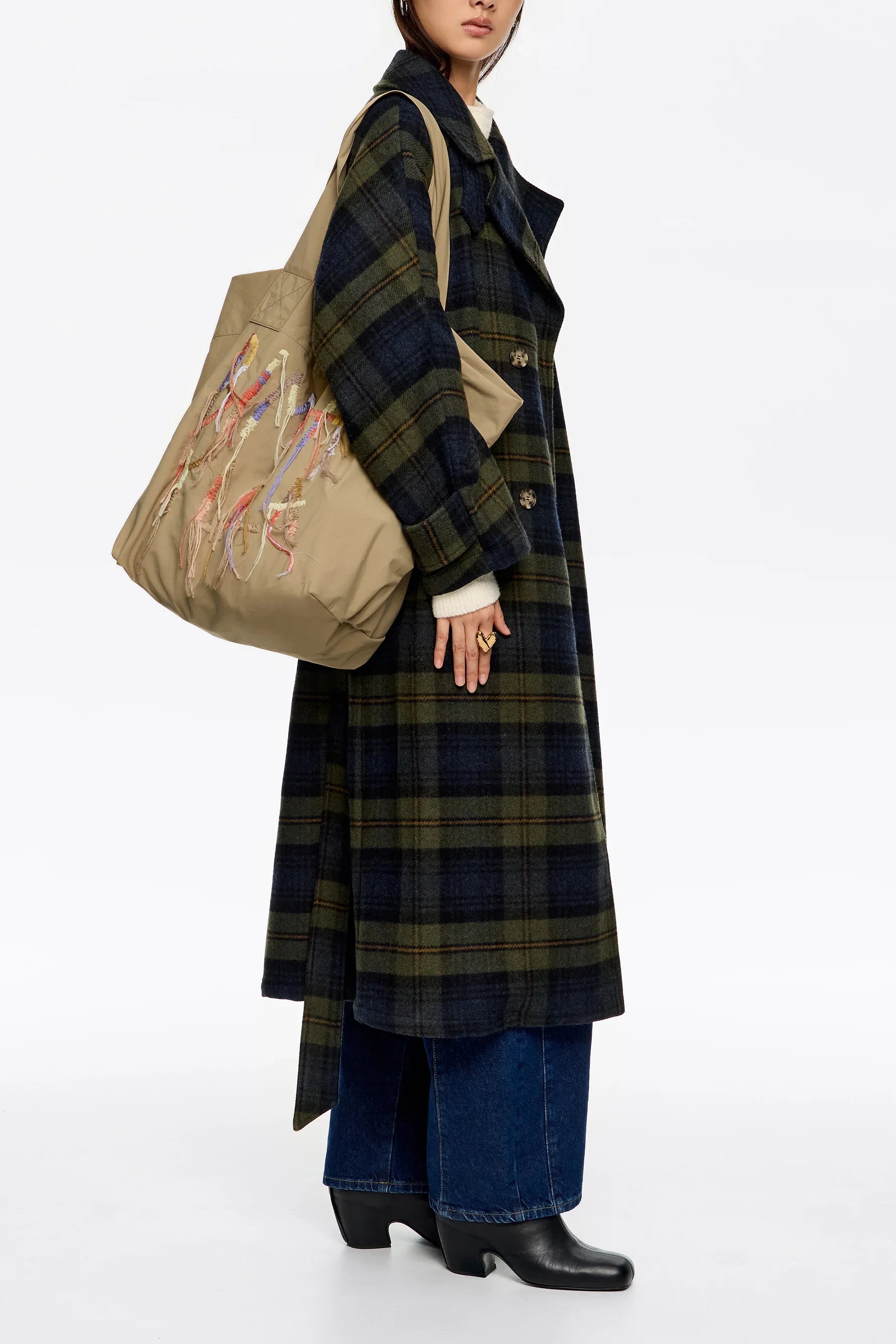 אישה עם מעיל משובץ בצבע כהה, תיק בז' עם רקמה צבעונית, אופנה CHOZEN