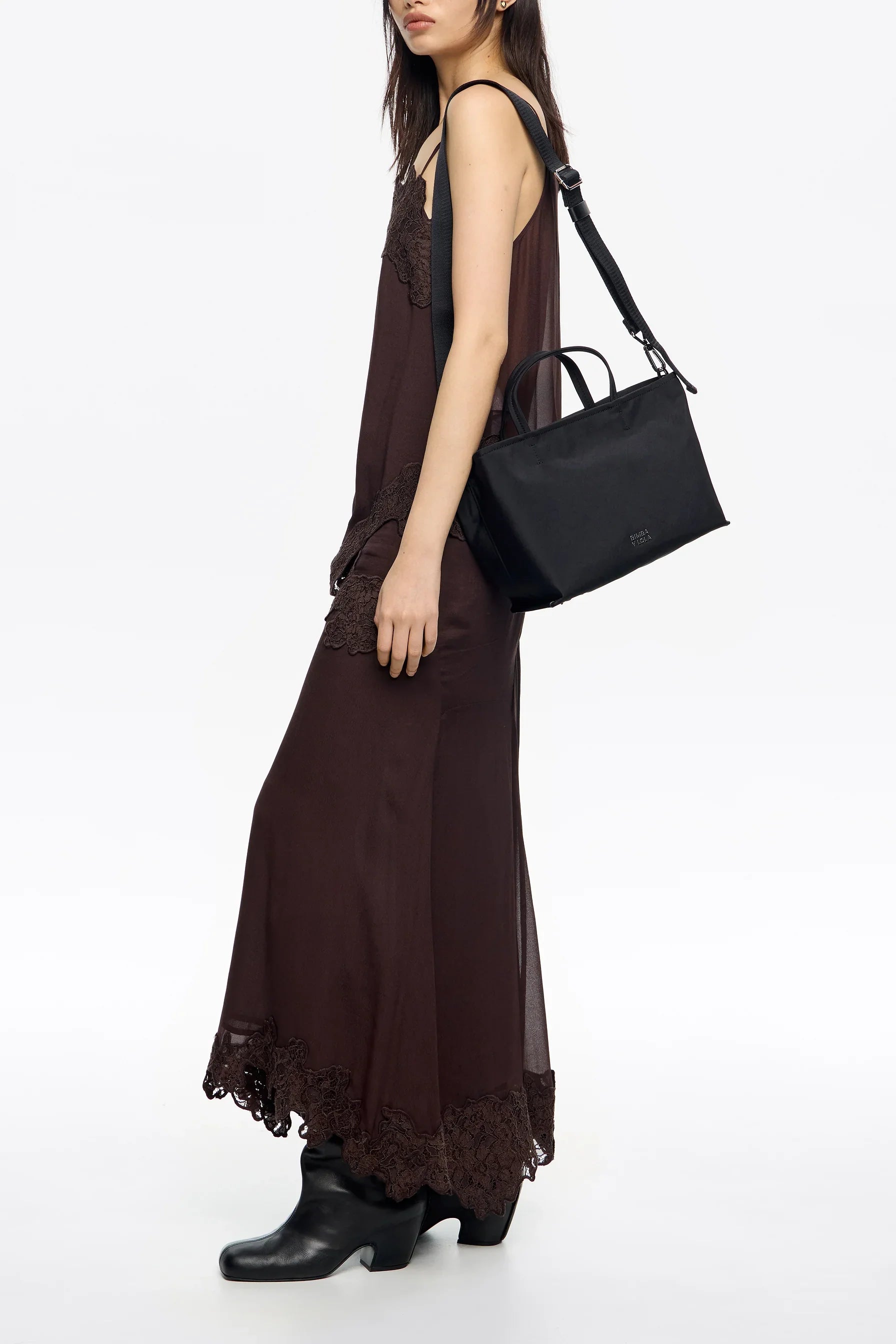 אישה בשמלה חומה ארוכה ונעלי עור שחורות עם תיק צד שחור, אופנת CHOZEN