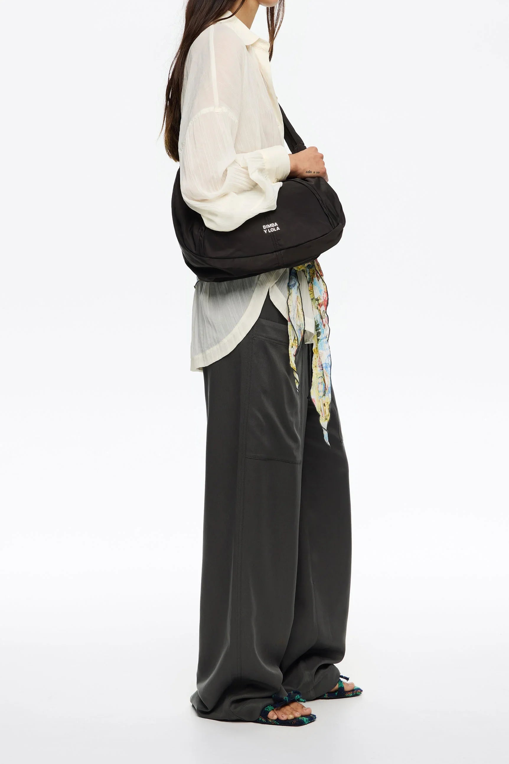 אישה עם חולצה לבנה, מכנסיים רחבים שחורים, תיק כתף Bimba Y Lola באתר CHOZEN