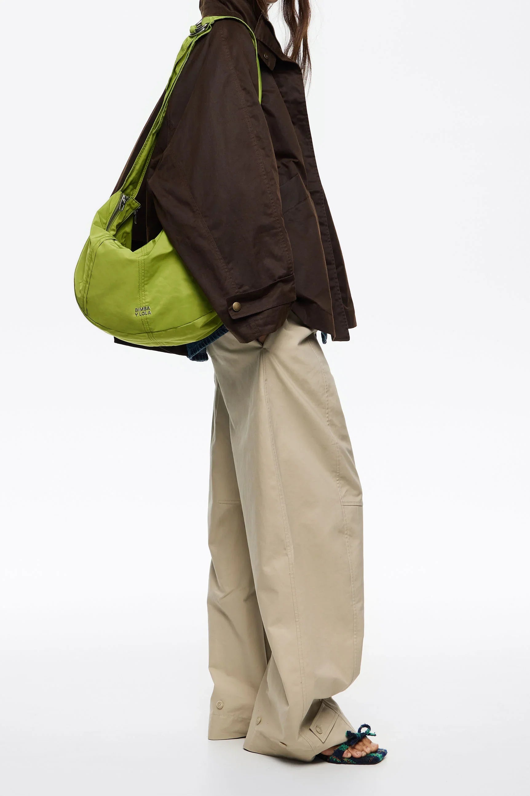 אופנה מבית CHOZEN - אישה עם תיק ירוק בולט, מעיל חום ומכנסיים רחבים בז', לוק מודרני וטרנדי