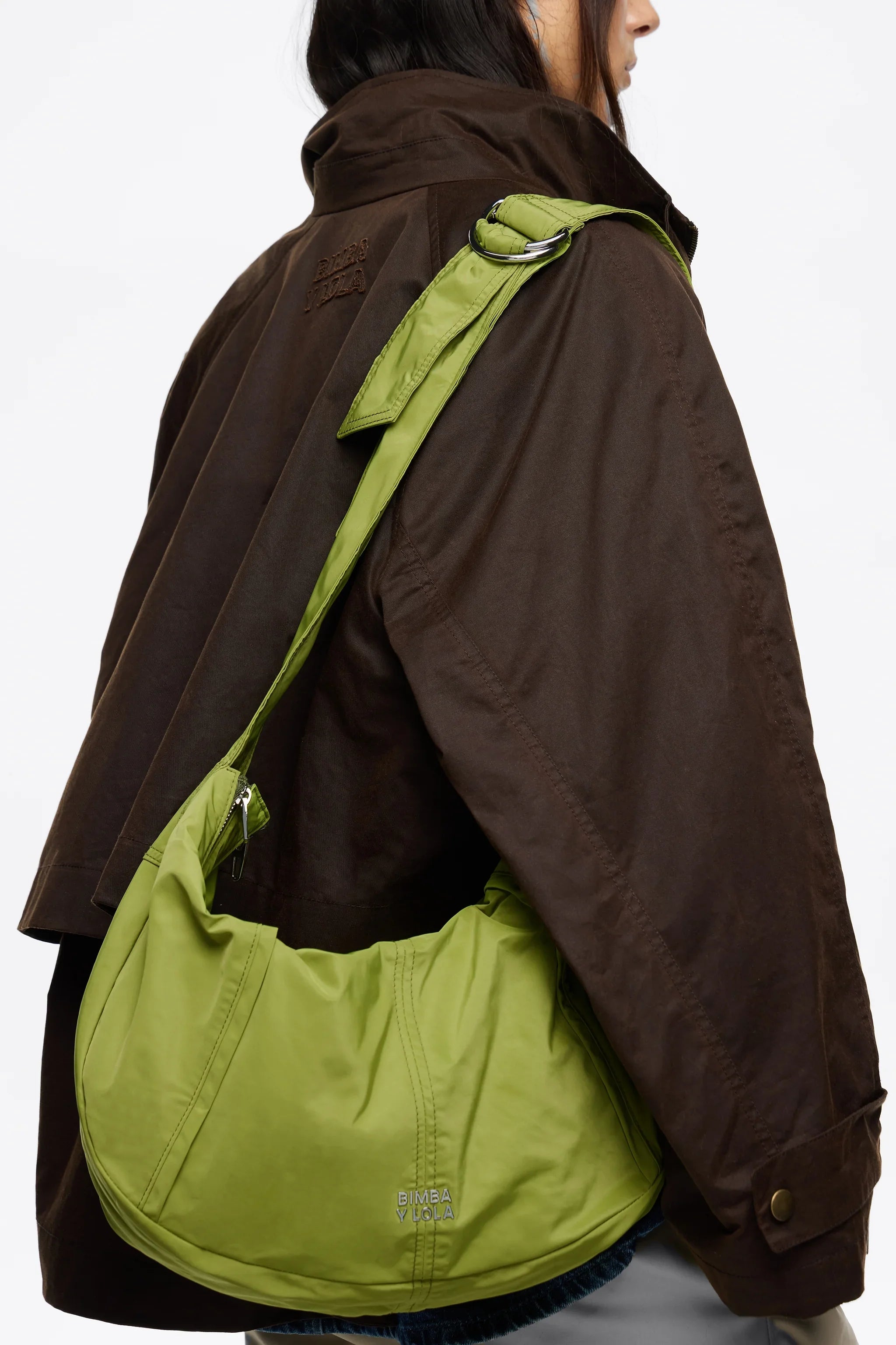 תיק ירוק של BIMBA Y LOLA על כתף של אישה עם מעיל חום, אופנה יוקרתית CHOZEN