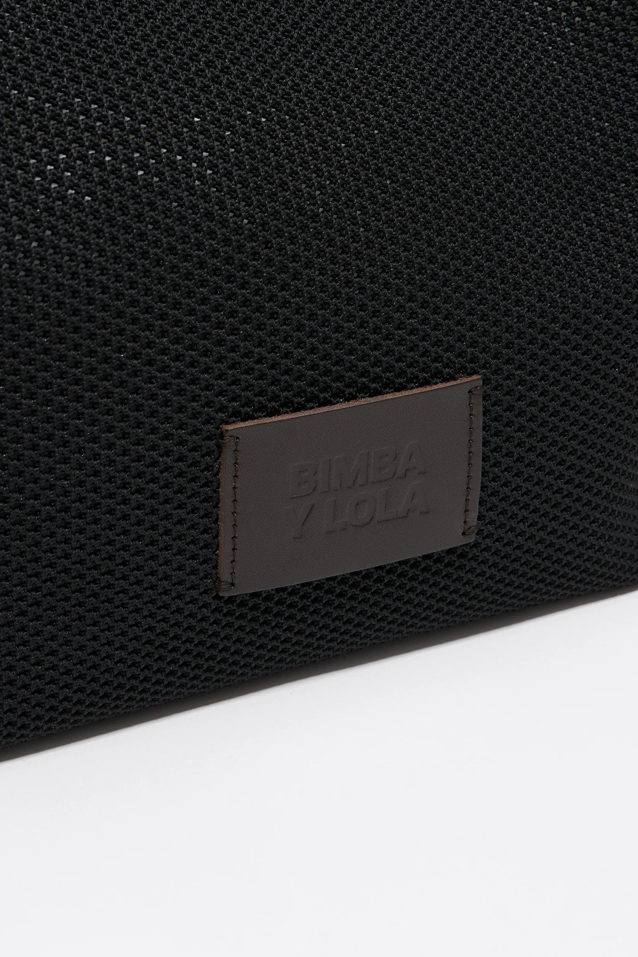 תקריב תיק שחור טקסטורה, תג עור עם כיתוב BIMBA Y LOLA, מותג בינלאומי ב-CHOZEN