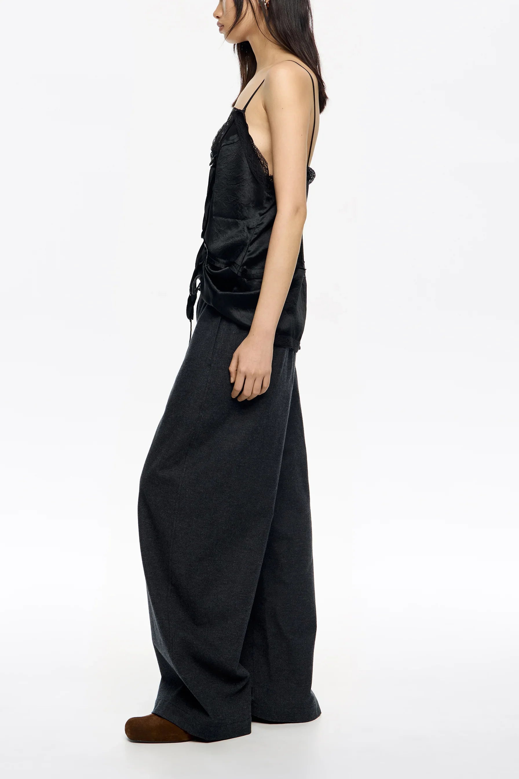 אישה עם גופיית סאטן שחורה ומכנסיים רחבים כהים, אופנה מודרנית CHOZEN