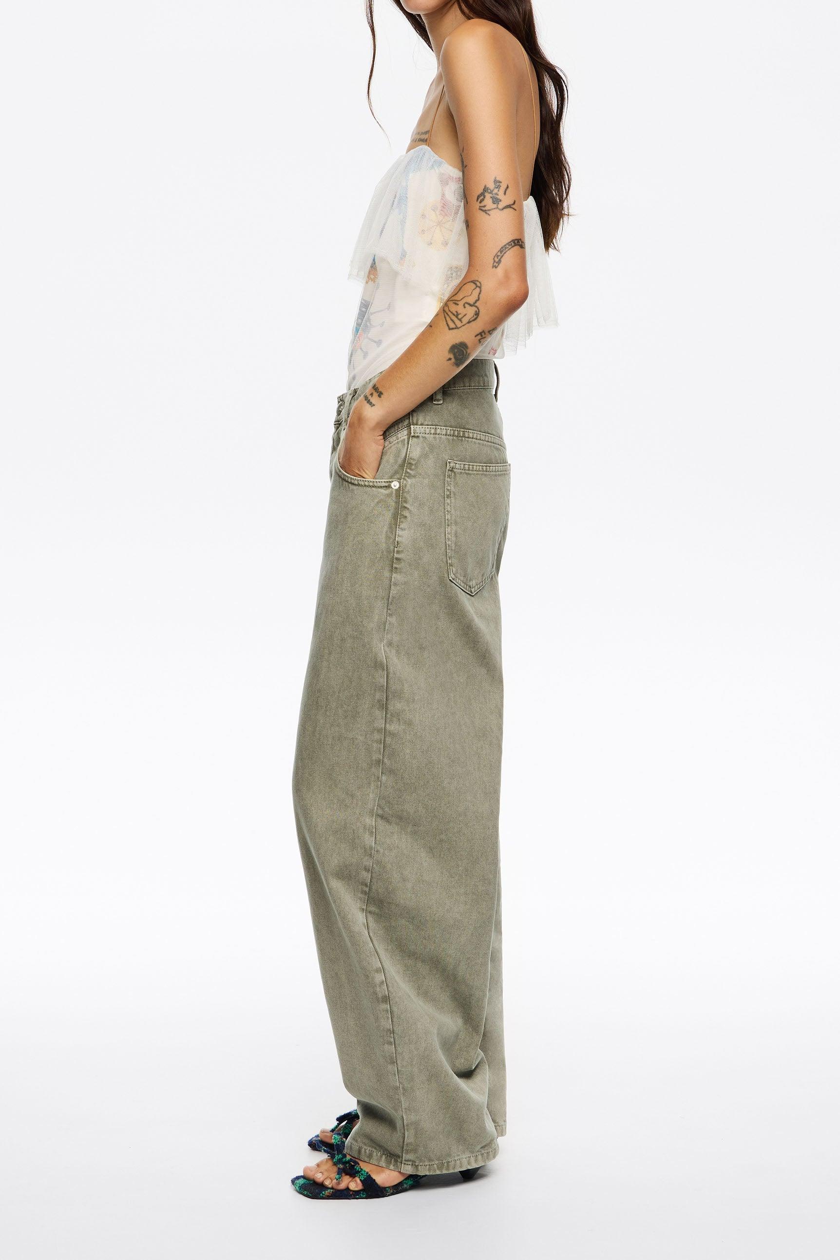 דגם נשי עם מכנסיים בגזרת ג'ינס רחבה בצבע חאקי, טופ קליל ונעליים פתוחות, אופנה טרנדית ב-CHOZEN