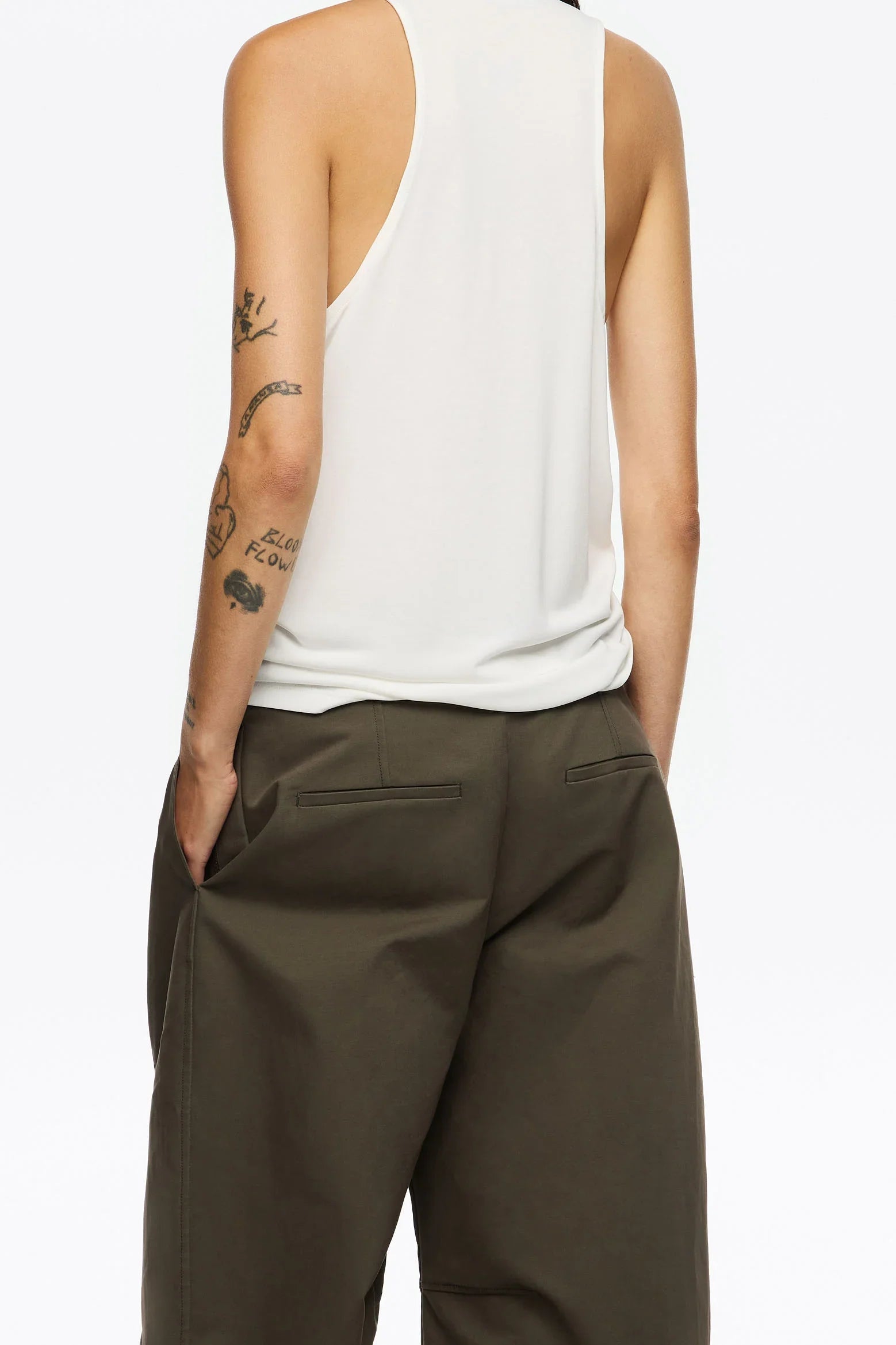 דגם לובש גופייה לבנה ומכנסיים ירוקים, קעקועים על היד, צילום אופנה CHOZEN