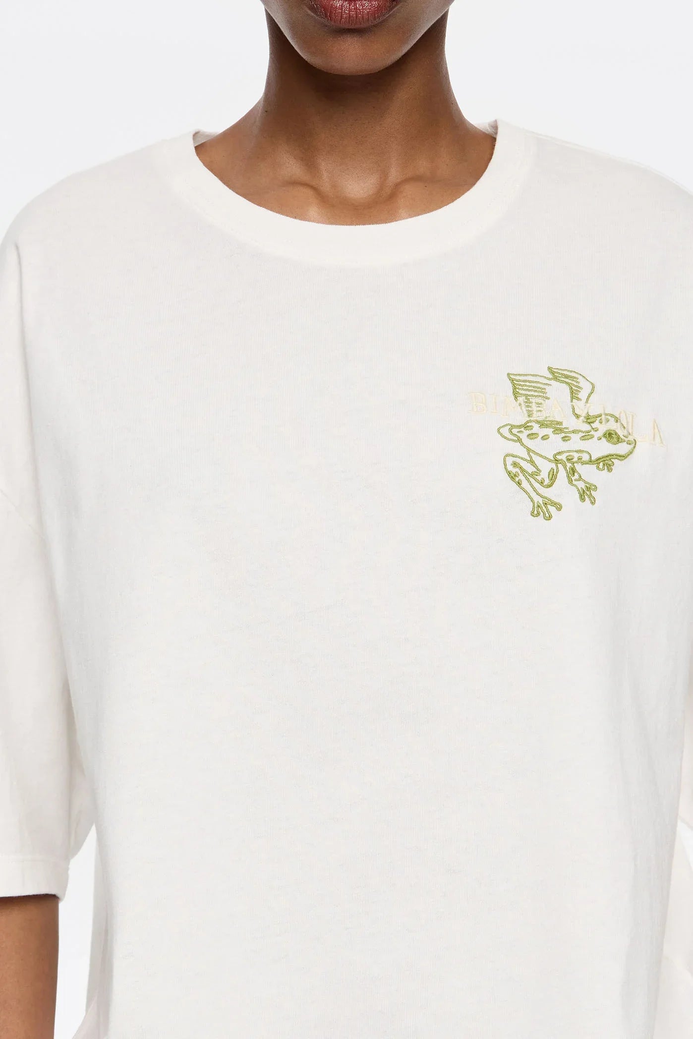 חולצת טי לבנה עם הדפס צפרדע ירוק בכנף, אופנת מעצבים ב-CHOZEN