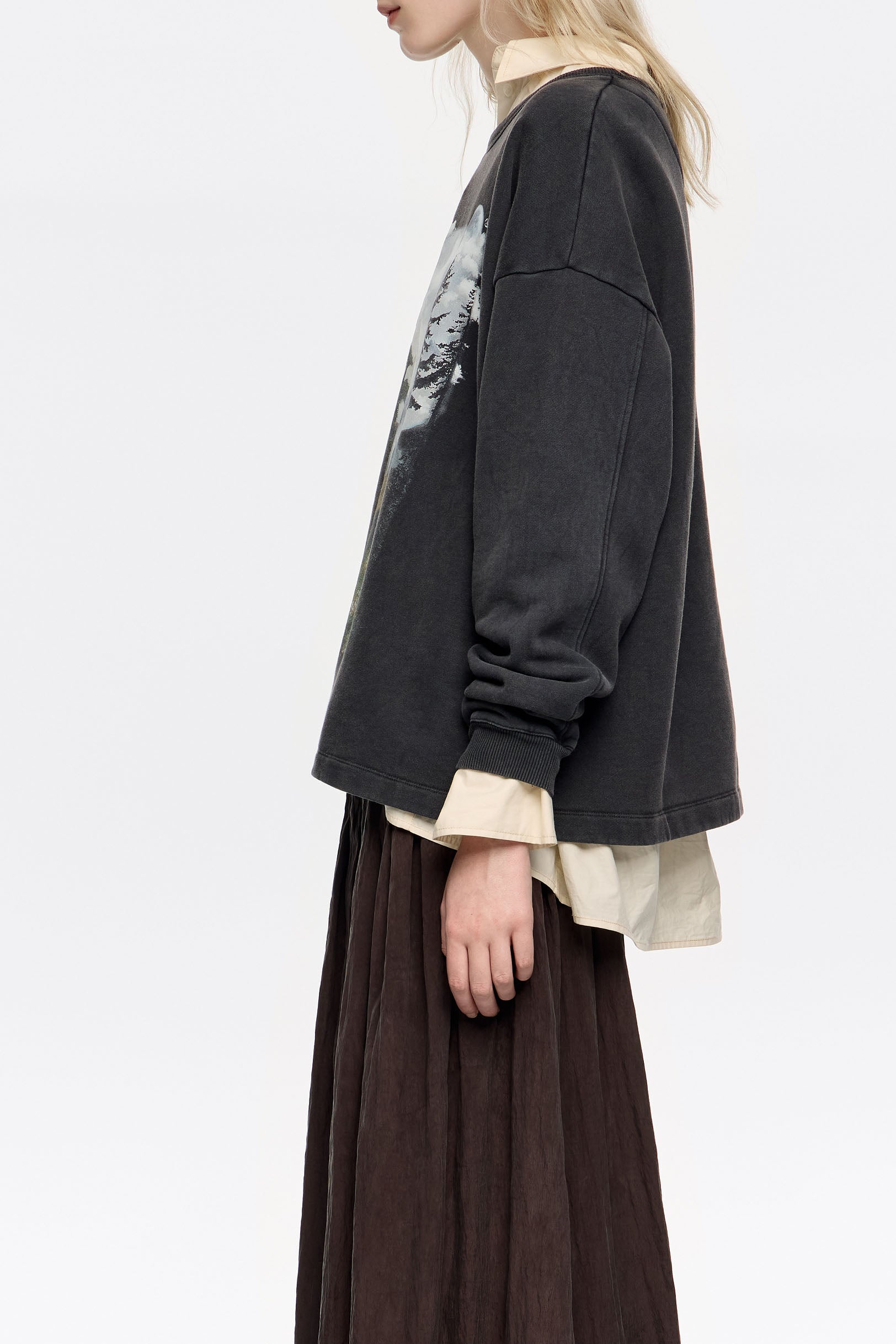 דוגמנית לובשת סווטשירט שחור עם חולצה בהירה וחצאית חומה, אופנת CHOZEN אלפא