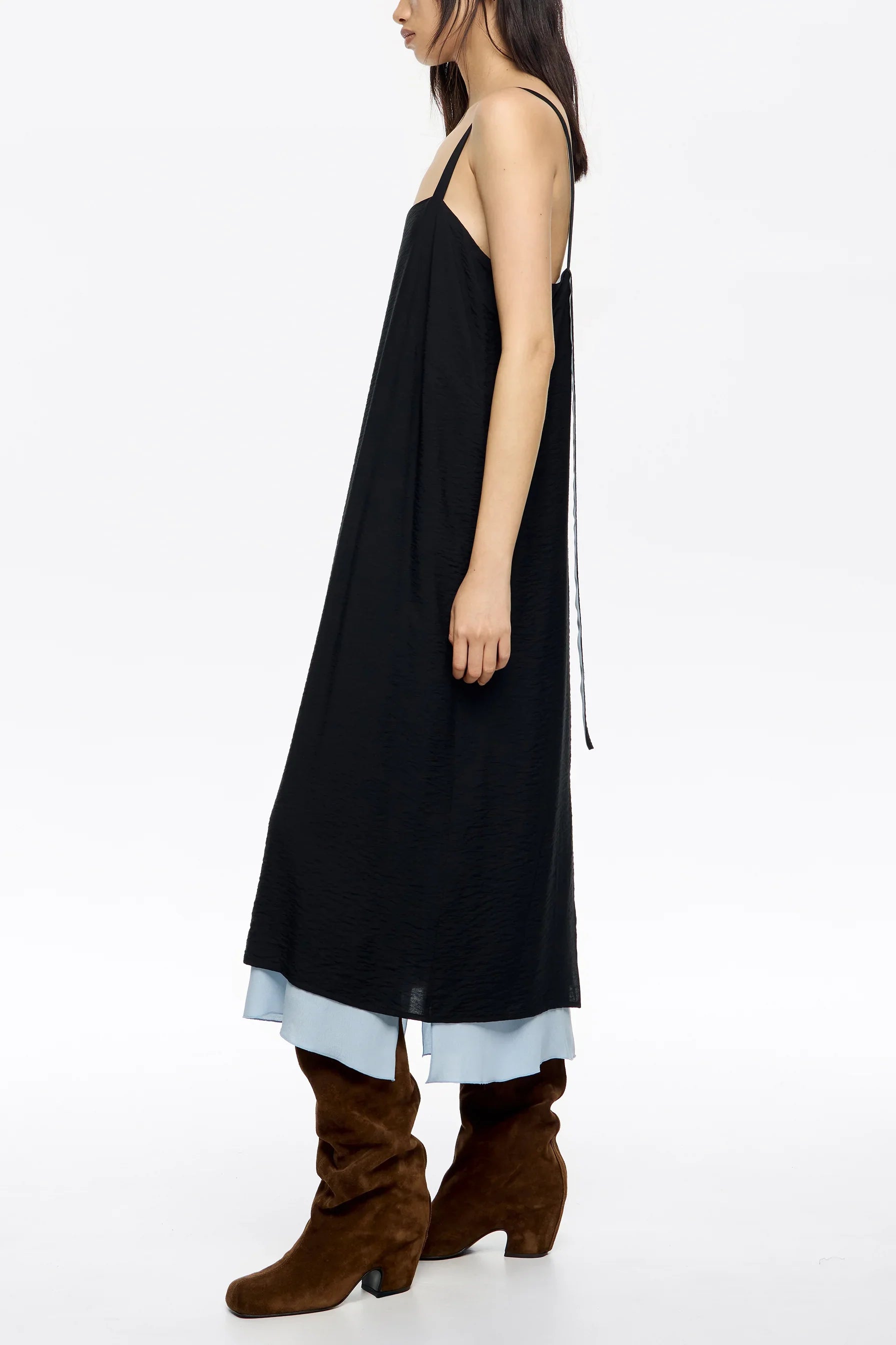 דוגמנית לובשת שמלה שחורה בשכבות עם כתפיות דקות ומגפיים חומים, צילום סטודיו, CHOZEN