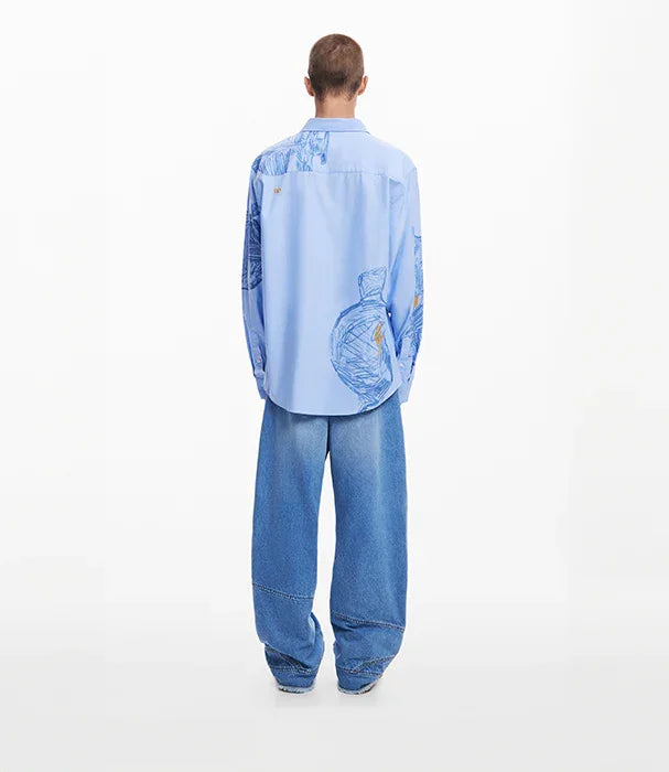 גבר מדגים חולצה כחולה עם הדפס גרפי ומכנסי ג'ינס רחבים, צילום אופנה לחנות CHOZEN