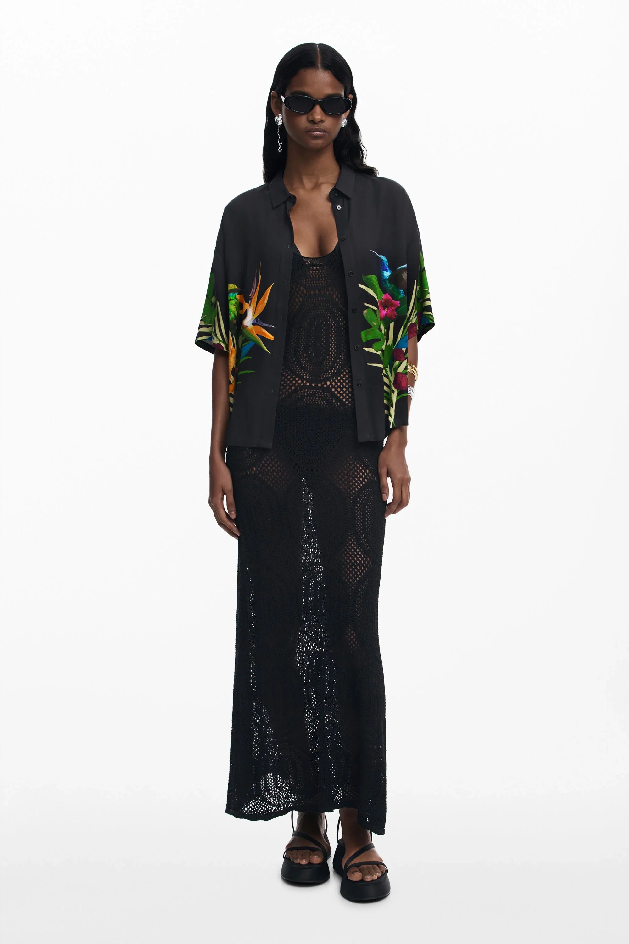 דוגמנית בשרשרת, משקפי שמש, שמלת רשת שחורה וחולצה שחורה עם הדפס פרחוני צבעוני, אופנה טרנדית CHOZEN