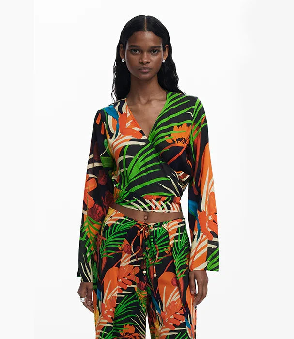 אישה לובשת חליפת טרופית צבעונית עם הדפס צמחים ירוק, כתום ושחור, אופנת CHOZEN