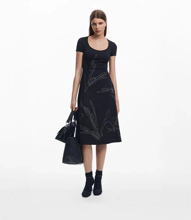 אישה עם שמלת מעצבים שחורה מודפסת ודגם פרחים, תיק יד, אופנה CHOZEN קבוצת אלפא