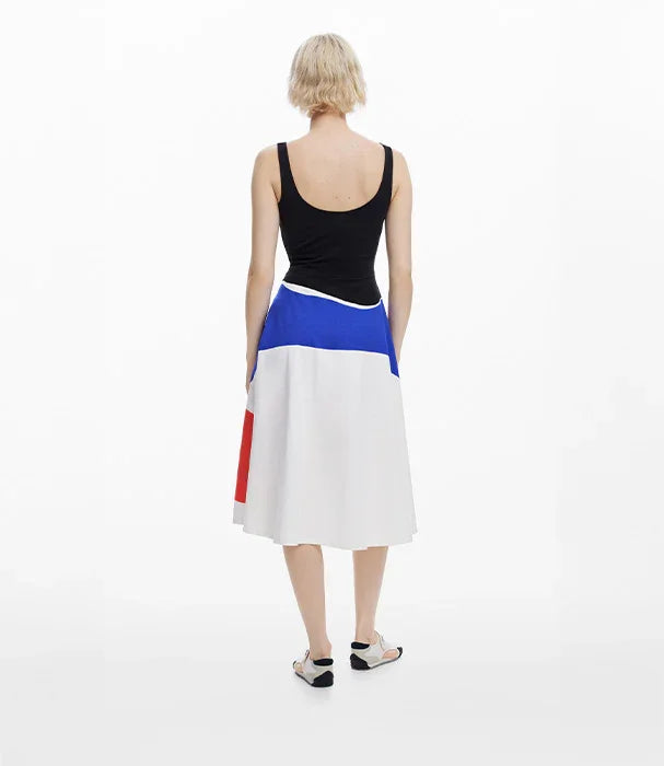 אישה עם שמלה בצבעים שחור, כחול, לבן ואדום עומדת מול רקע לבן, אופנה CHOZEN