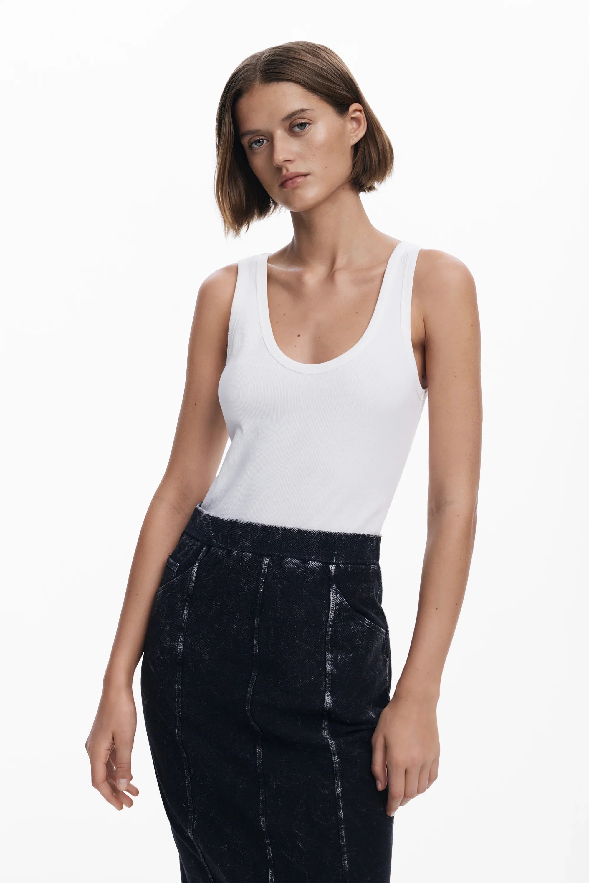 דוגמנית לובשת טופ לבן ללא שרוולים וחצאית כהה, צילום אופנה לאתר CHOZEN של קבוצת אלפא