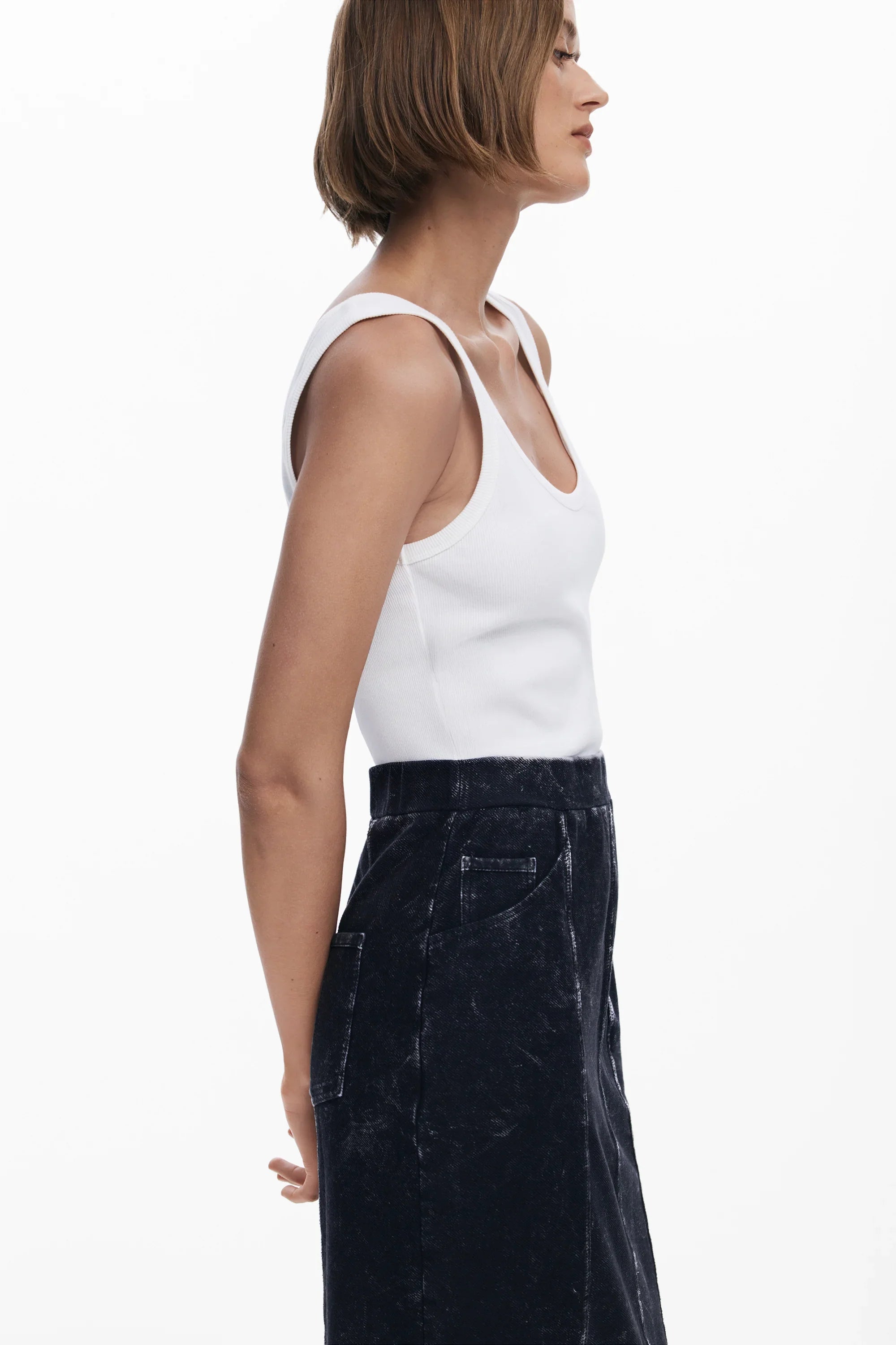 אישה עם גופיית טנק לבנה וחצאית כהה, אופנת נשים מבית CHOZEN קבוצת אלפא