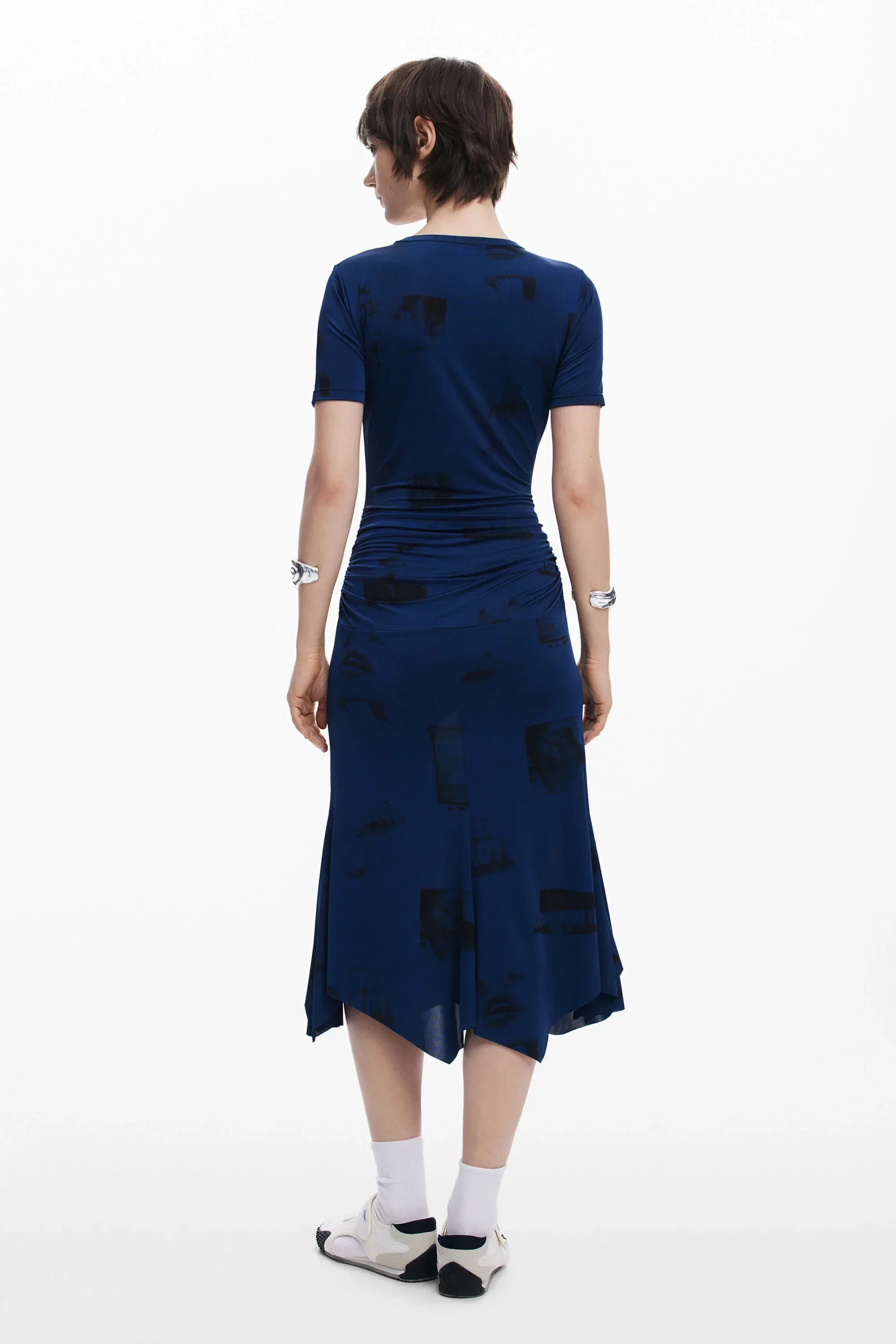 אישה בשמלה כחולה עם הדפס כהה עומדת על רקע לבן, אופנת CHOZEN קולקציית מותגים מובילים
