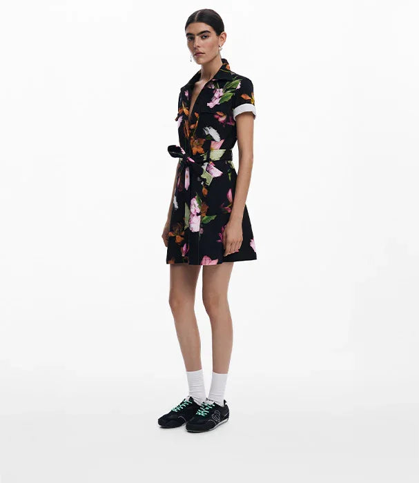 דוגמנית לובשת שמלה שחורה עם הדפס פרחוני קייצי, נעלי ספורט שחורות, רקע לבן, CHOZEN