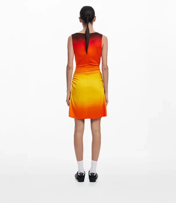 אישה בשמלת קיץ מדורגת כתום-צהוב, גב חשוף, על רקע לבן, אופנת CHOZEN