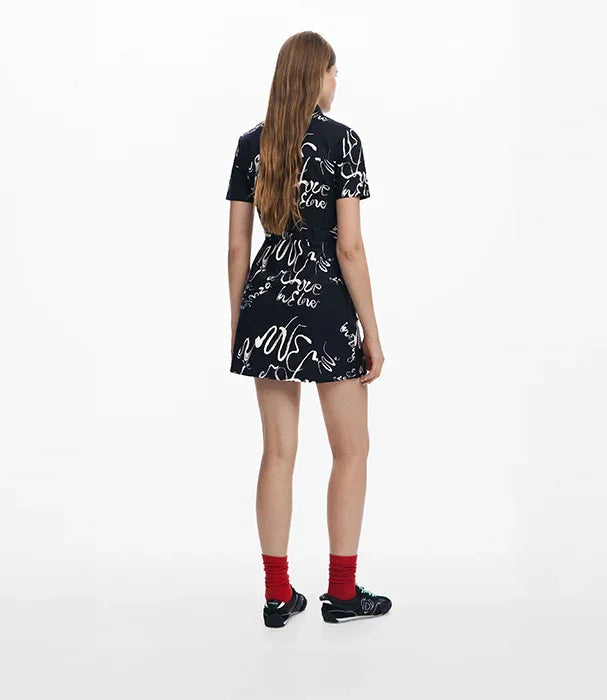 אישה בשמלת מיני שחורה עם הדפס לבן, גרביים אדומות ונעליים שחורות, צילום באולפן רקע לבן, CHOZEN