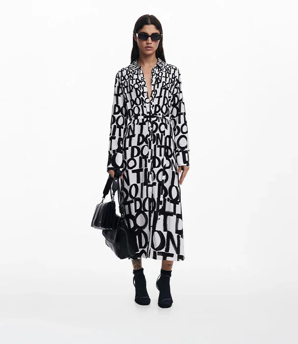 דוגמנית לובשת שמלה שחורה-לבנה עם הדפס אותיות, משקפי שמש ותיק שחור, אופנת CHOZEN