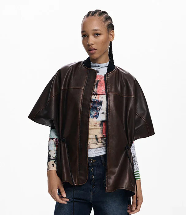 אישה מדגמנת ג׳קט עור חום קצר, אופנת CHOZEN, חולצה מודפסת צבעונית ברקע לבן