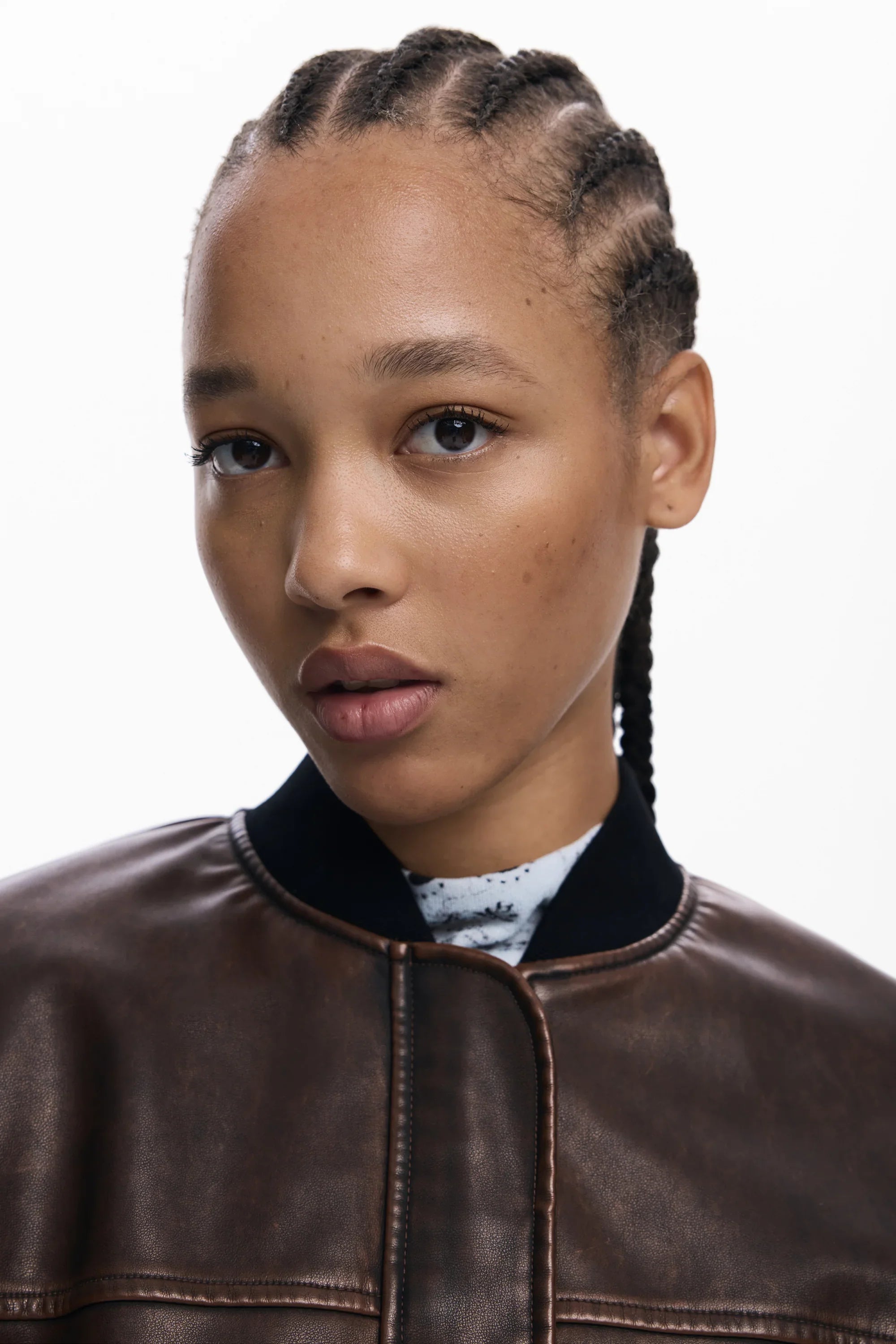 דוגמנית עם מעיל עור חום אופנתי, רקע לבן, צילום לאתר CHOZEN מותגי אופנה