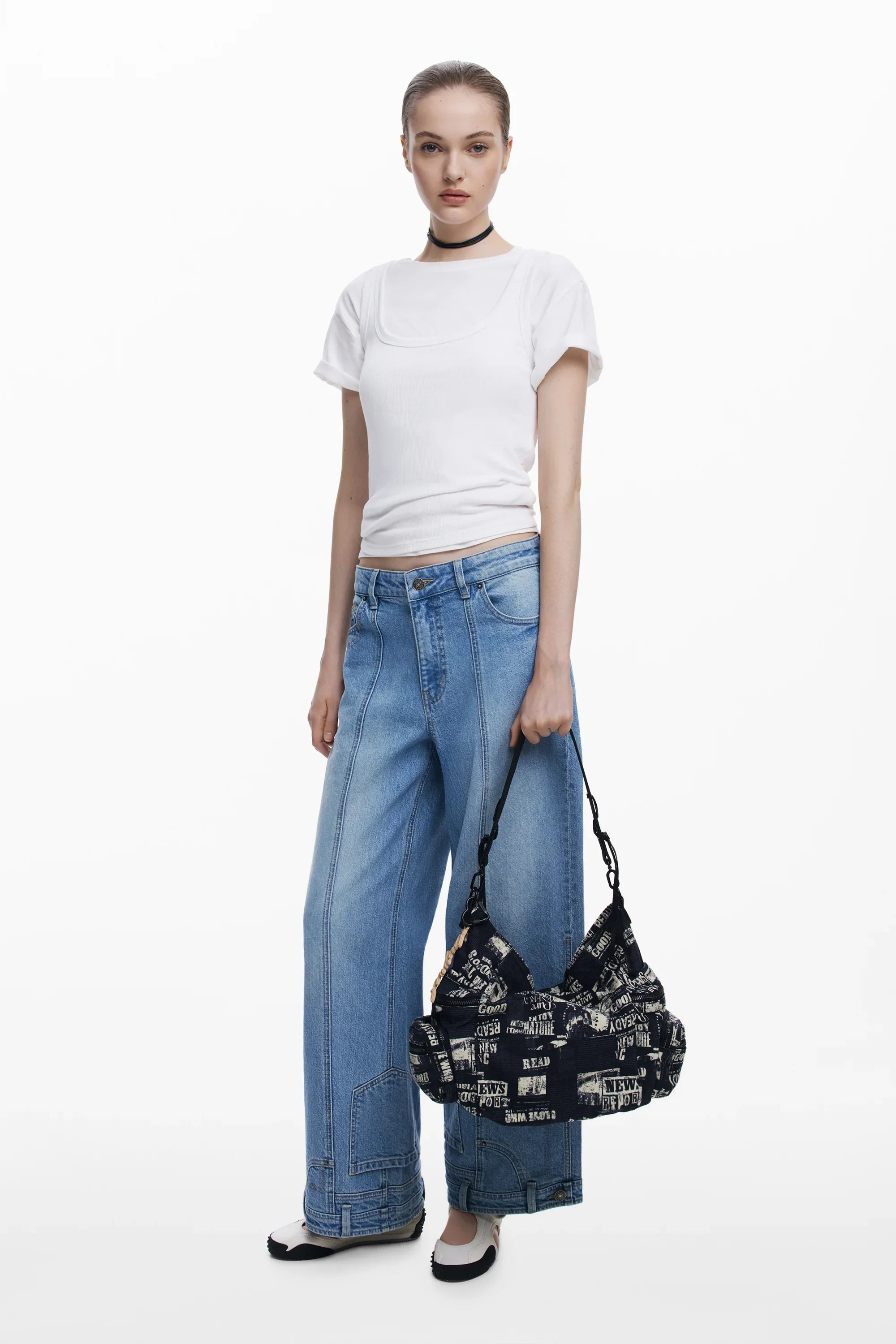 דוגמנית עם חולצה לבנה, ג'ינס רחב ותיק שחור עם הדפס כיתוב, CHOZEN אופנה לנשים