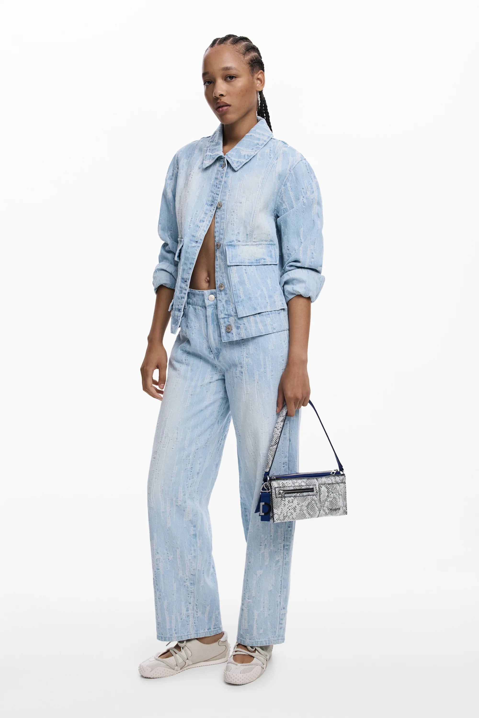 דוגמנית לובשת ג'קט ומכנסי ג'ינס בהירים עם תיק צד של מותג אופנה, CHOZEN