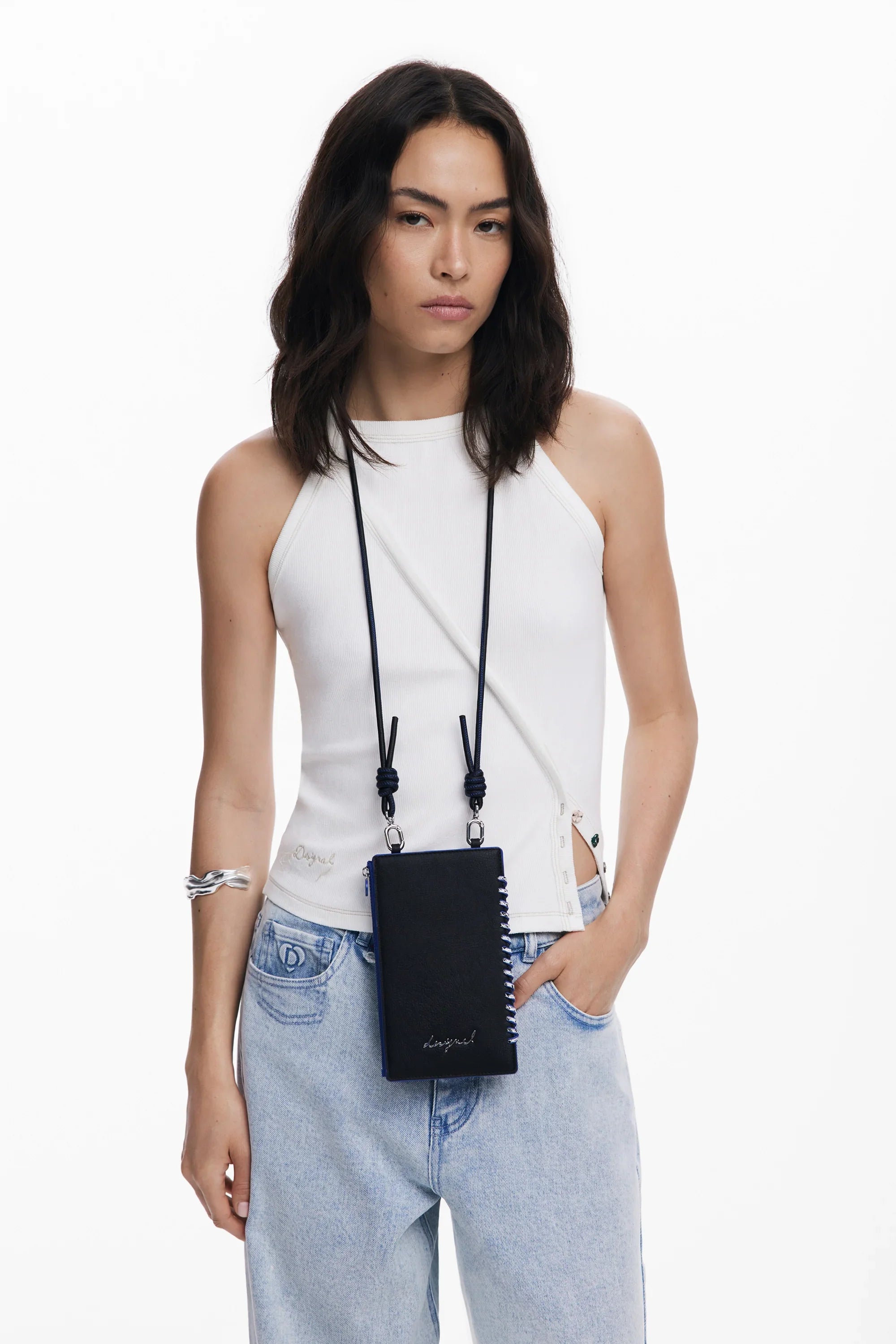 דוגמנית לובשת גופייה לבנה, ג'ינס תכלת וארנק שחור תלוי על צווארה, אופנה CHOZEN