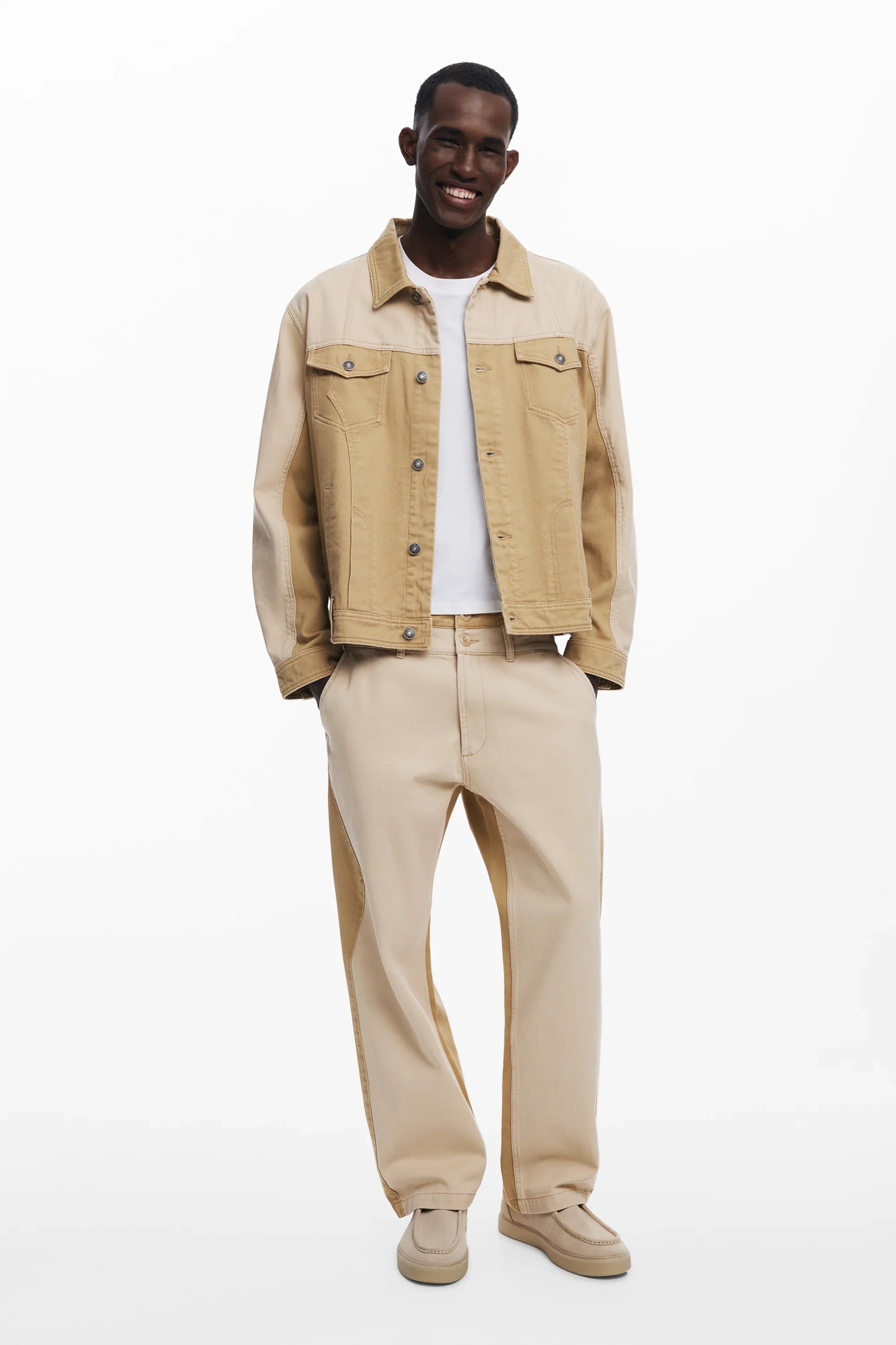 מודל גבר בחולצה לבנה, ז'קט ג'ינס ומכנסיים בגוון בז', אופנה CHOZEN קבוצת אלפא