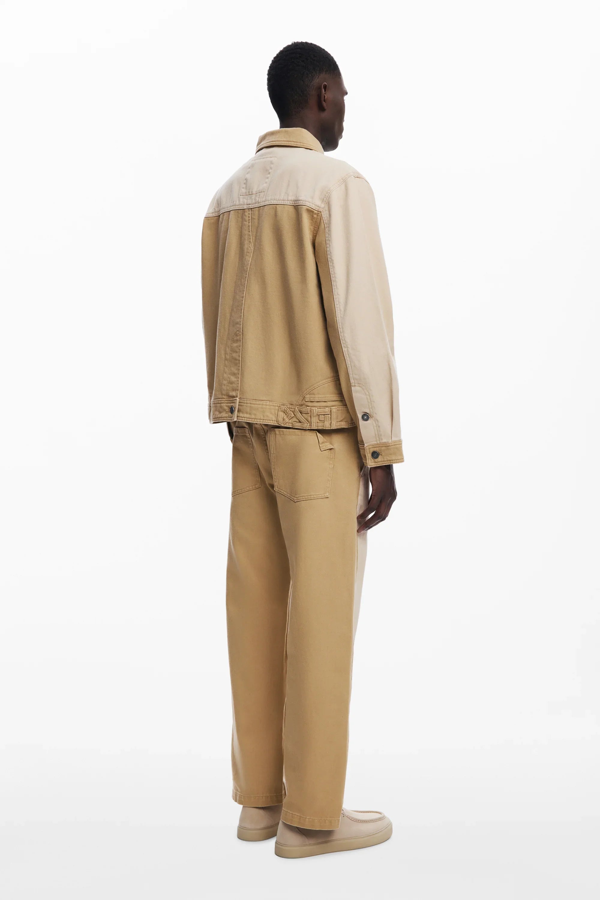 מודל גבר לבוש ג'קט ומכנסיים בגווני בז' מחברת CHOZEN, על רקע לבן