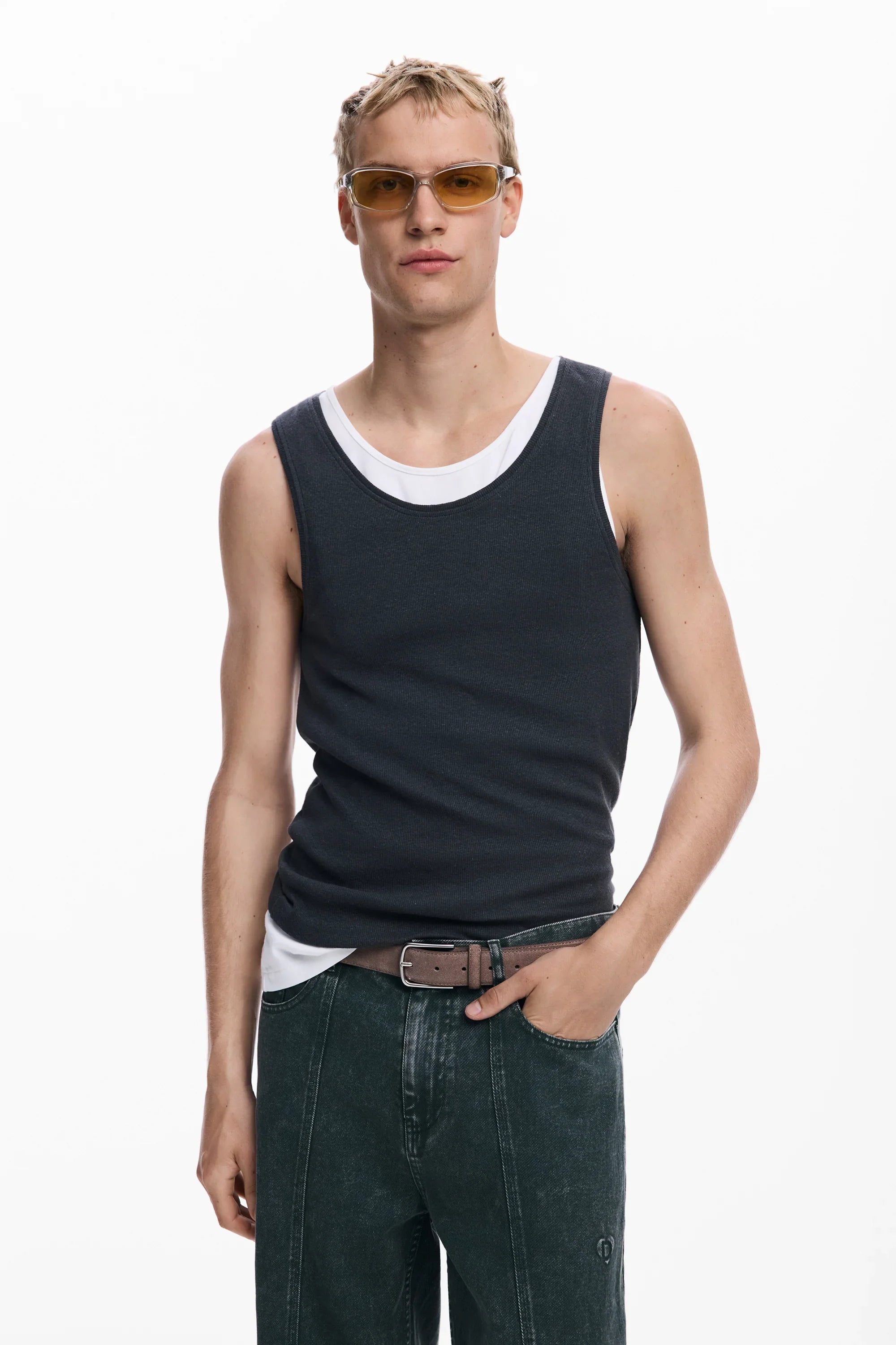 דוגמן עם משקפי שמש צהובות, גופיה שחורה, ג'ינס כהה וחגורה בעיצוב CHOZEN