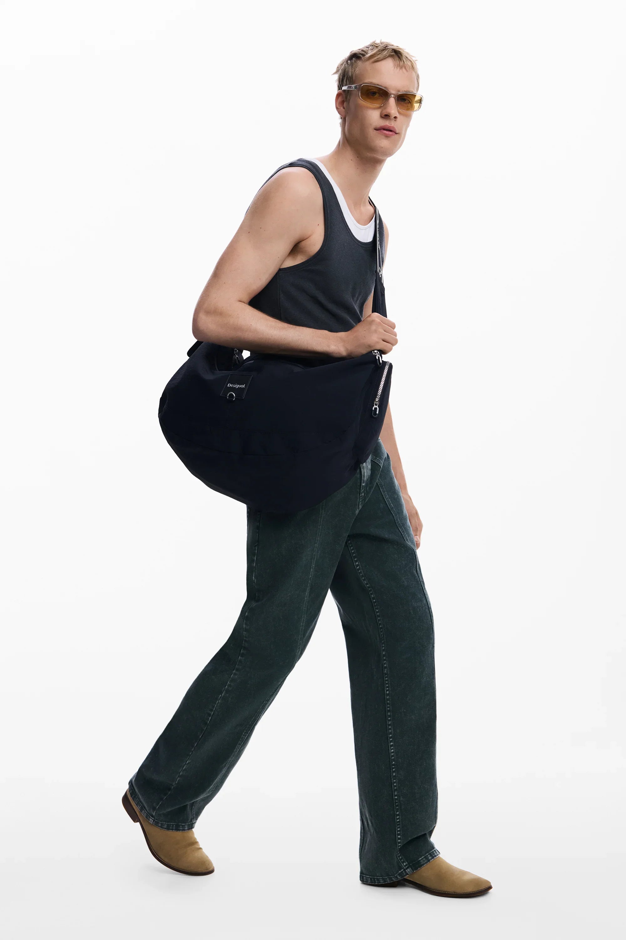 דגם גבר עם גופיית טי, מכנסיים רחבים, משקפי שמש ותיק צד שחור אופנתי מבית CHOZEN