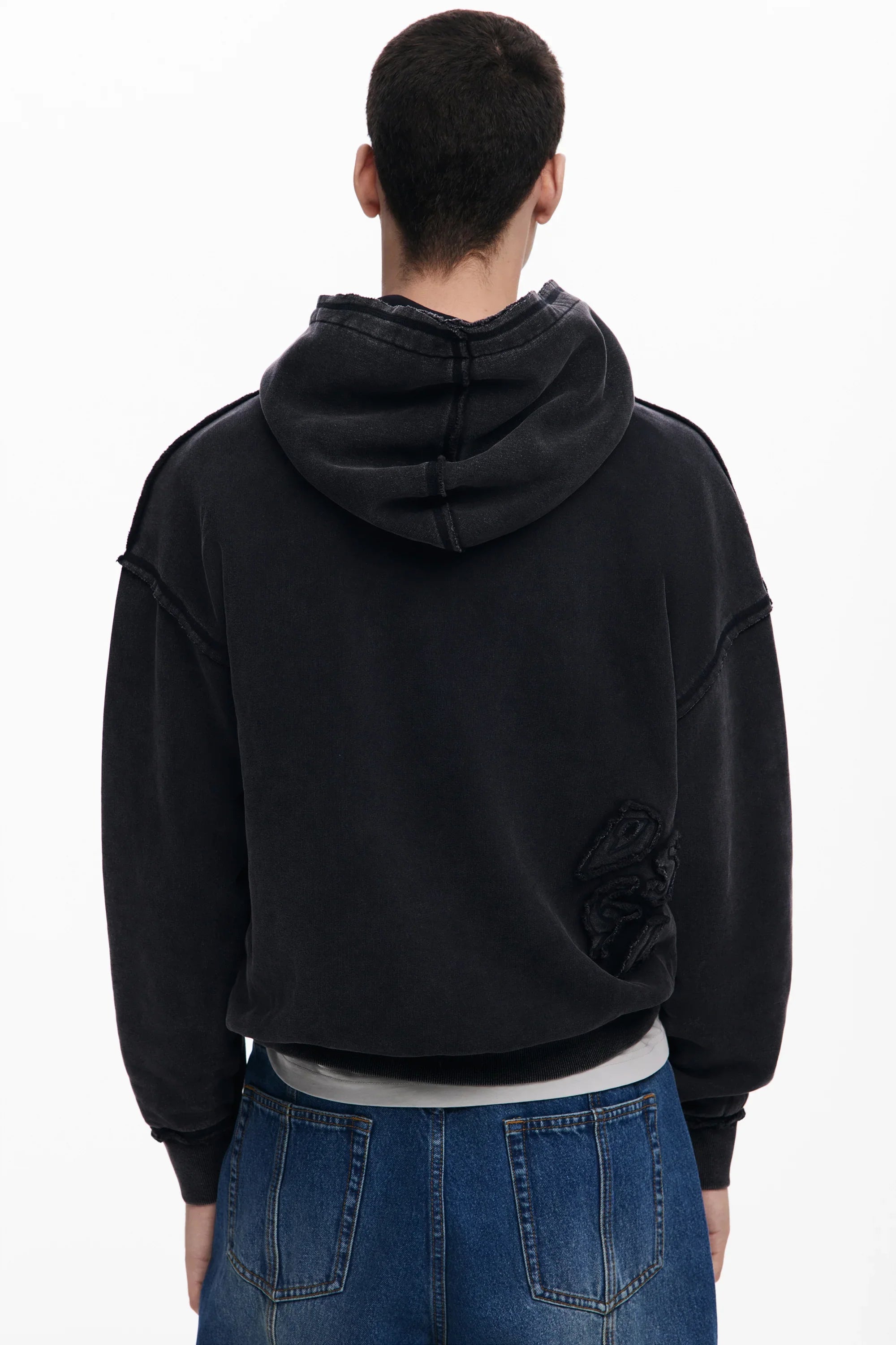 גבר עם קפוצ׳ון שחור אופנתי ומכנסי ג׳ינס כחולים, קולקציית CHOZEN מבית קבוצת אלפא