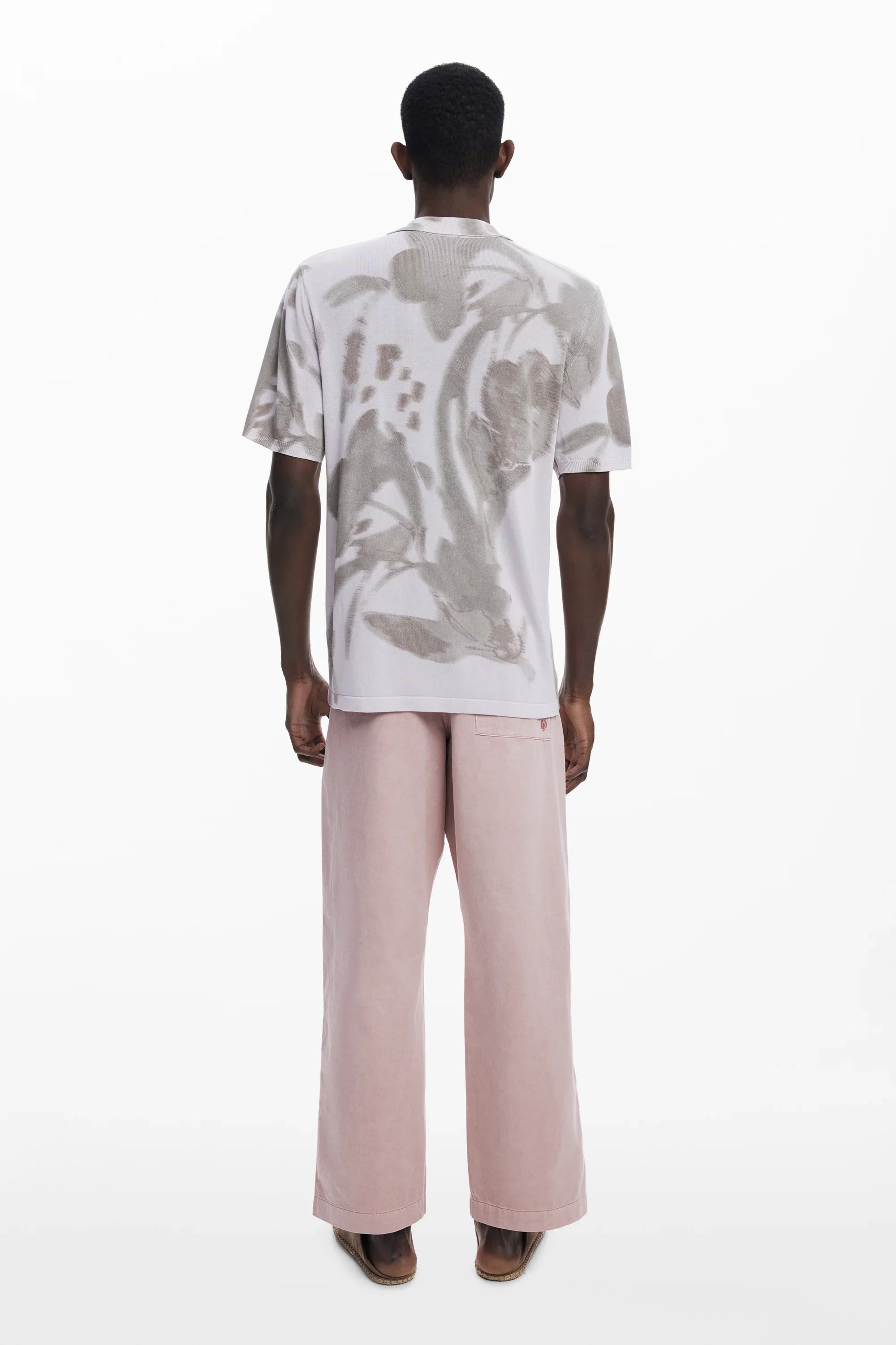 גבר לובש חולצה מודפסת בגווני אפור ומכנסיים ורודים רחבים, אופנת CHOZEN