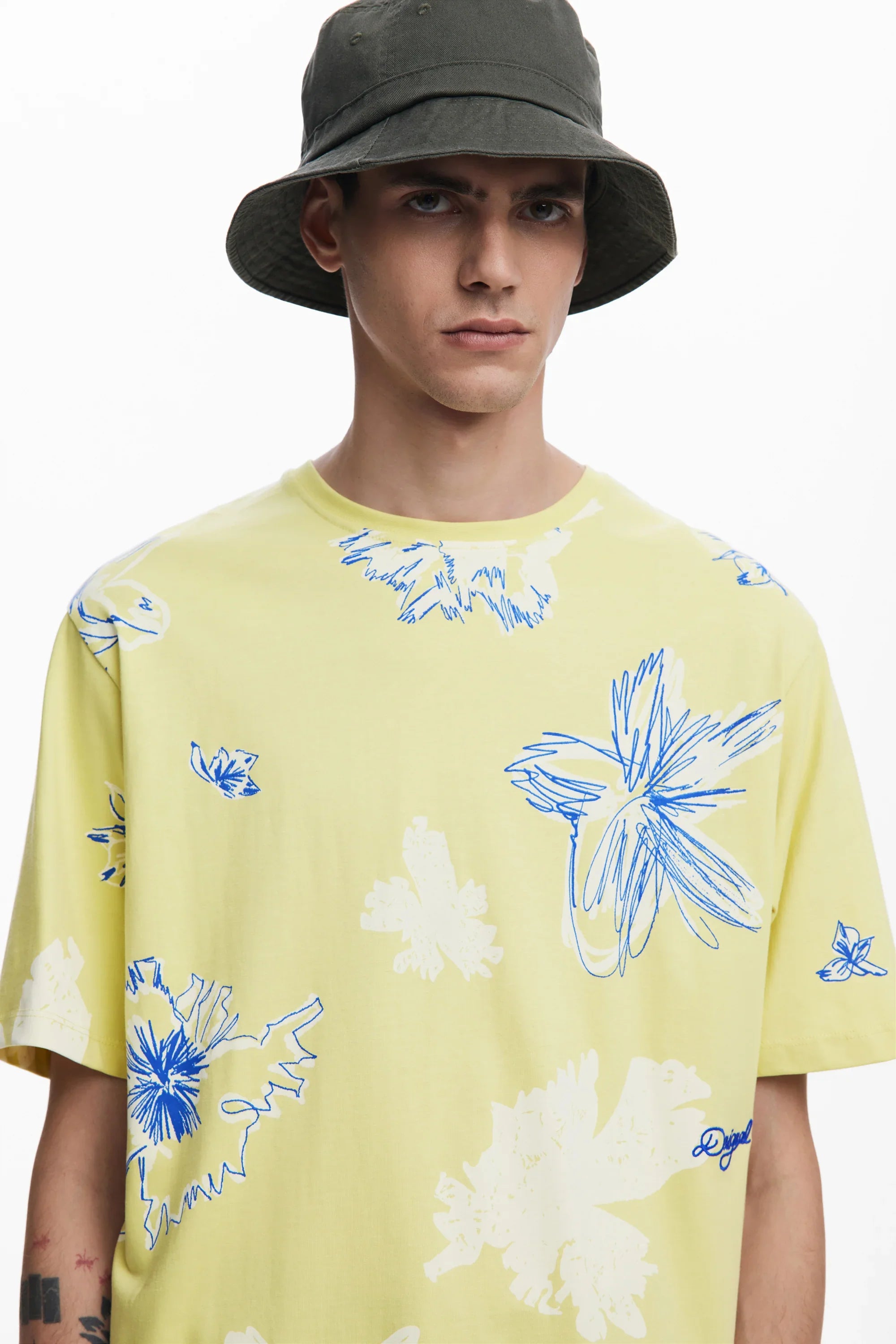 גבר עם כובע באקט וחולצת טי צהובה עם הדפס פרחוני, אופנה CHOZEN מותגים מובילים