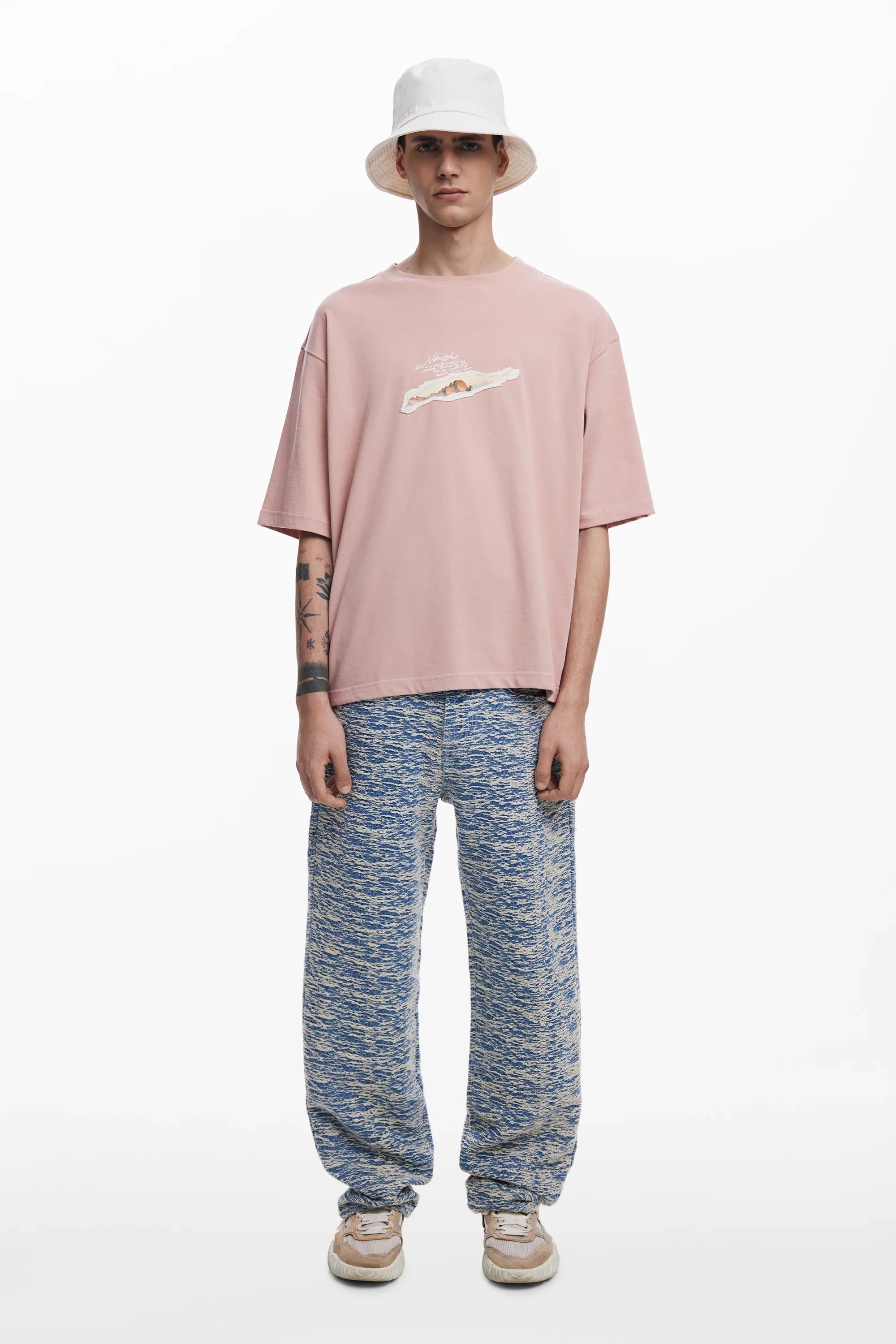 דוגמן לבוש חולצת טי ורודה, כובע באקט לבן ומכנסיים כחולים, אופנת גברים CHOZEN