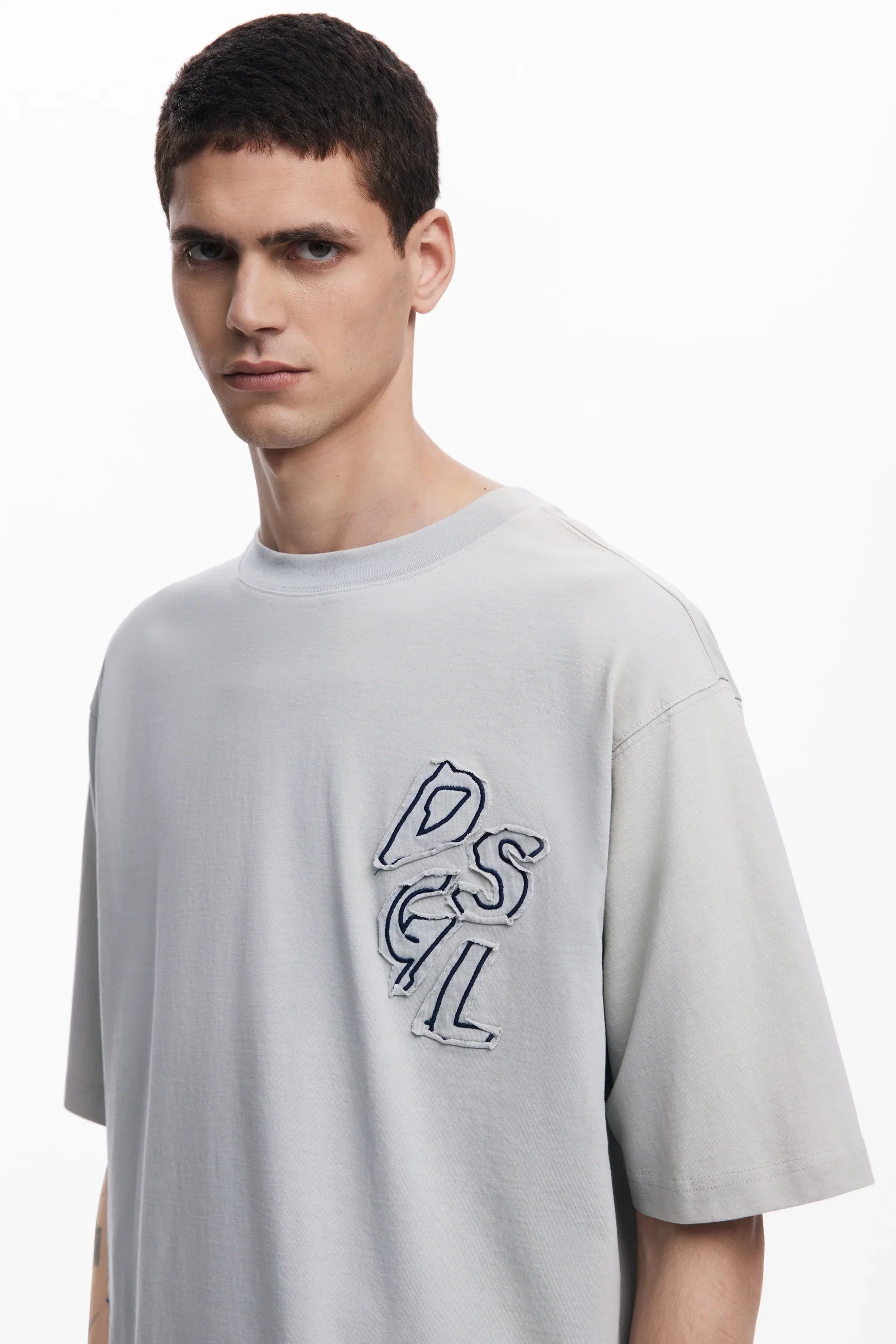 דגם גבר לובש טי שירט אפורה עם רקמת אותיות, מבית המותגים המובילים ב-CHOZEN