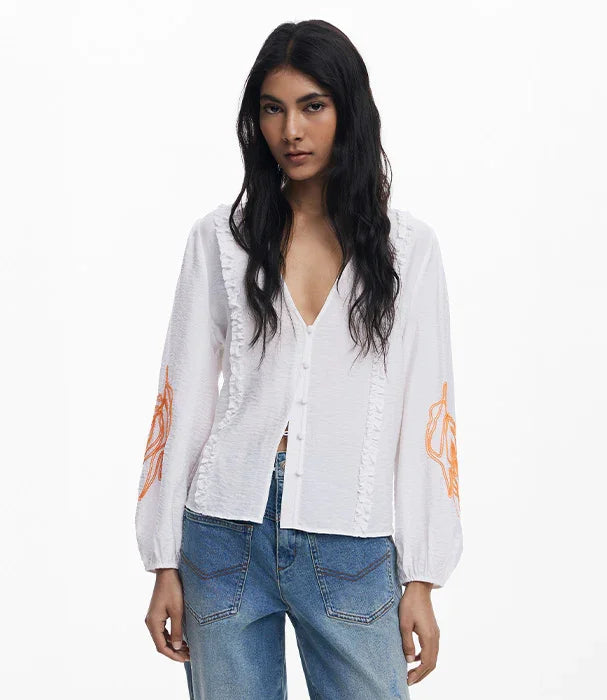דוגמנית לובשת חולצה לבנה עם רקמת כתום על השרוולים וג'ינס, אופנה טרנדית בחנות CHOZEN