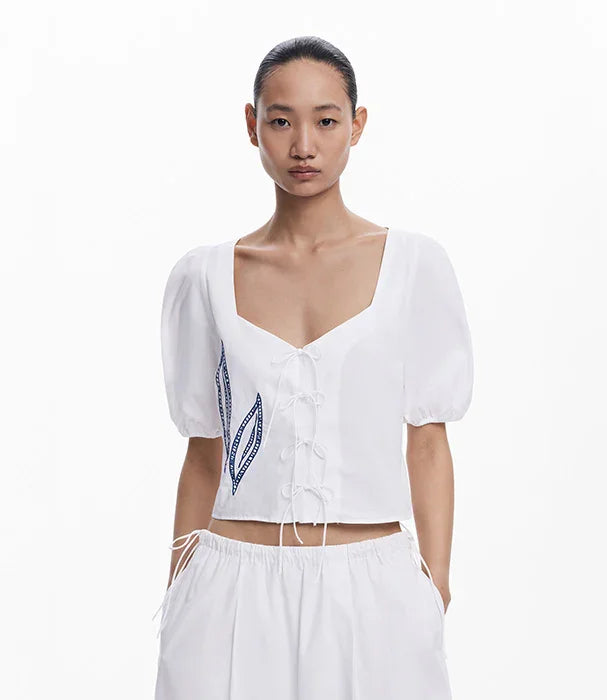 חולצת נשים לבנה עם שרוכים ושרוולים תפוחים, עיטור עלים כחול, צילום אופנה ל-CHOZEN