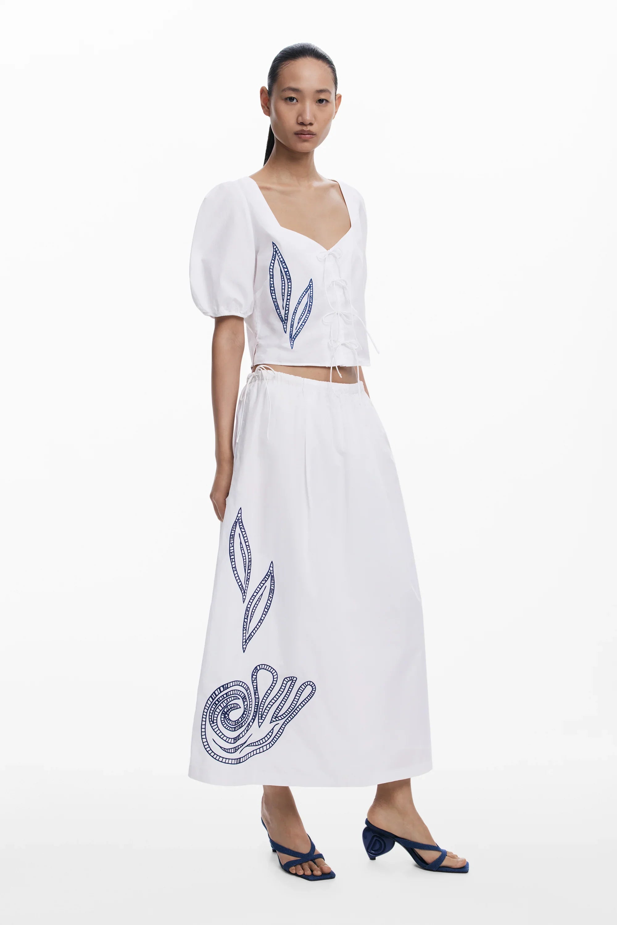 אישה עם סט חצאית וחולצה לבנה עם הדפסים כחולים בעיצוב אופנתי, CHOZEN מותגים מובילים